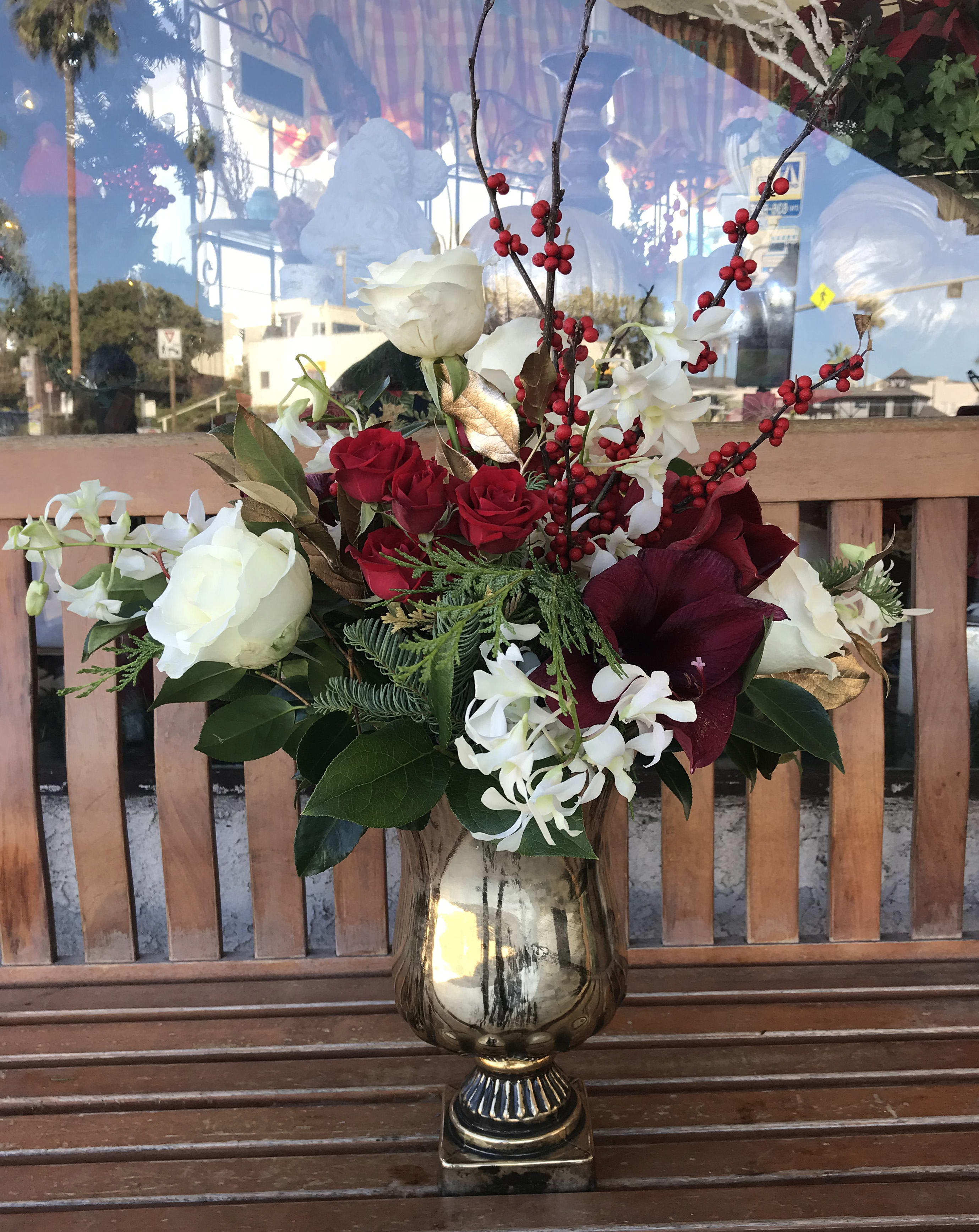 Golden Holiday - A rich, beautiful arrangement in a festive holiday vase. Contains all of our favorite seasonal flowers with berries and pine.