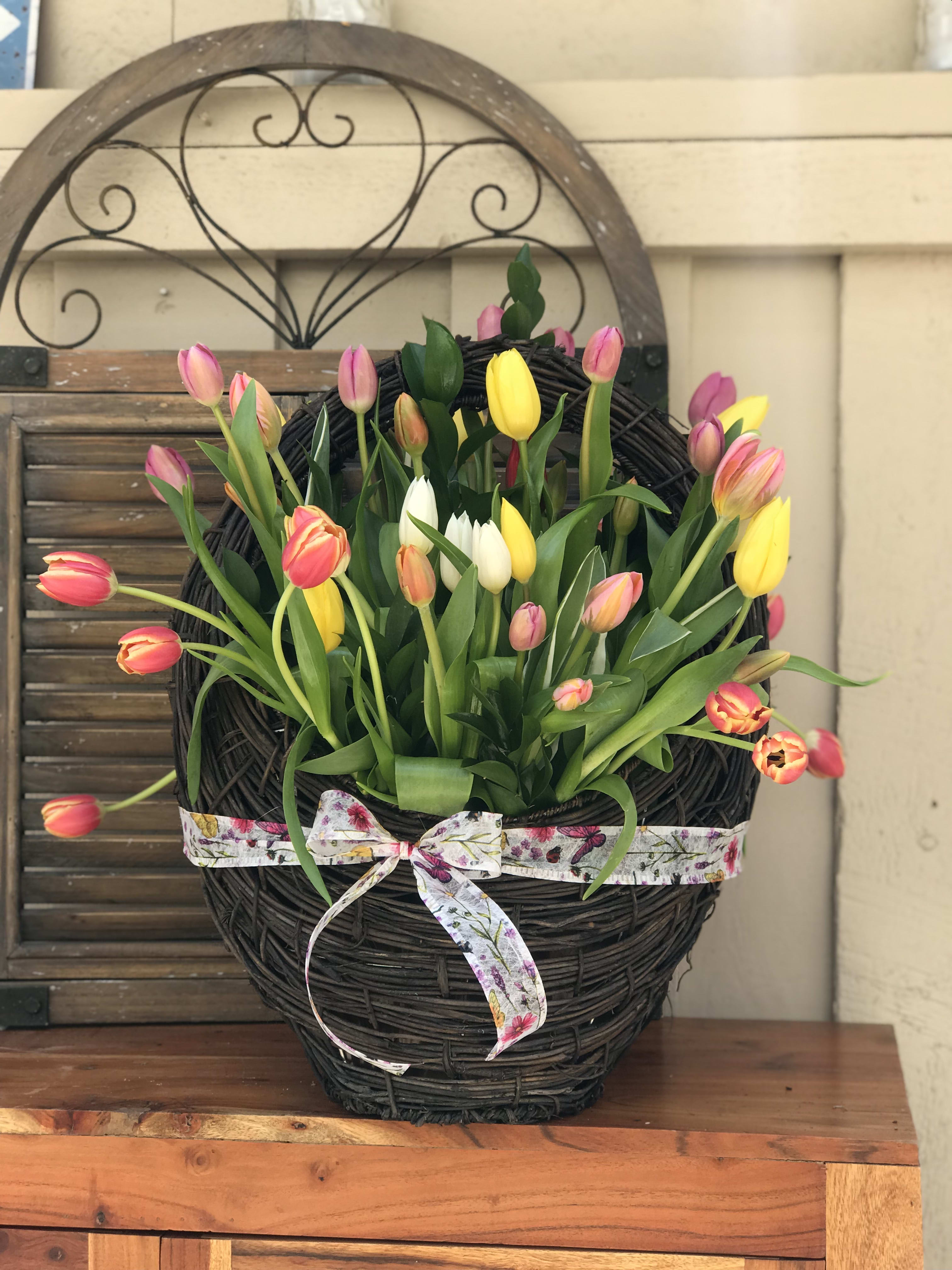 Basket arrangement of pink, yellow, and white tulips with a ribbon