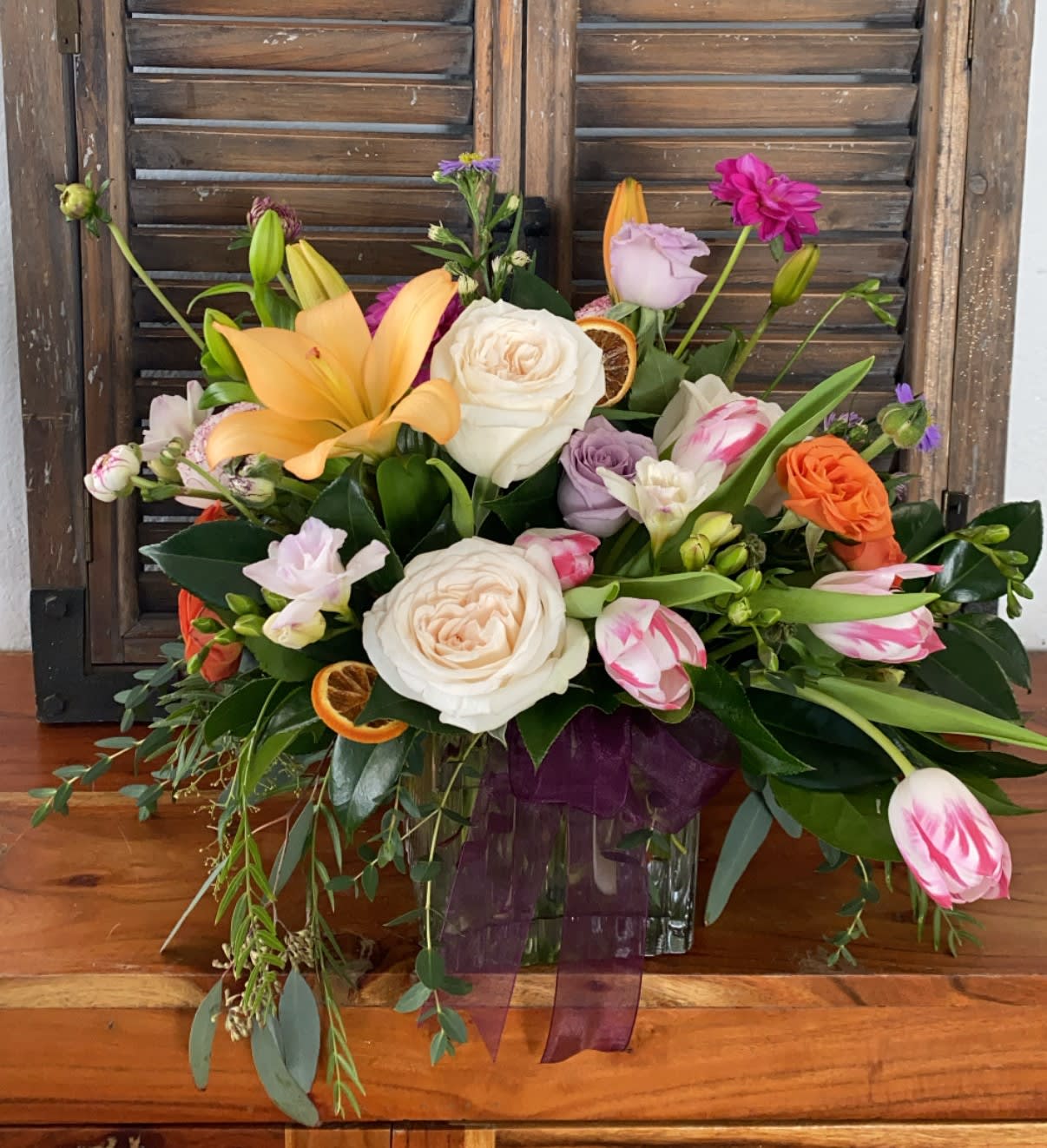 Mixed bouquet with roses, lilies, and tulips in a glass vase