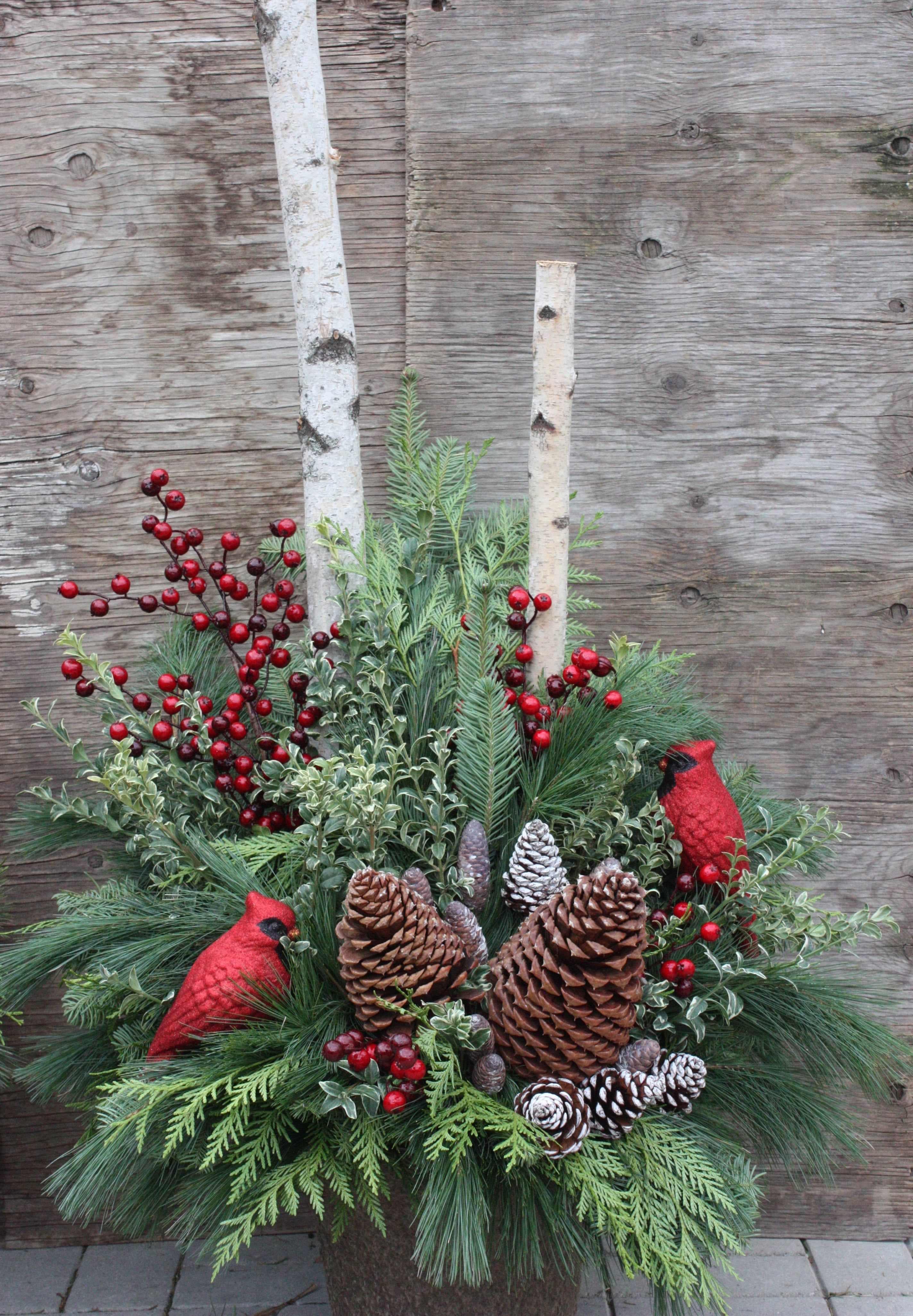 Holiday arrangement with pine, berries, pinecones, and red cardinal figurines