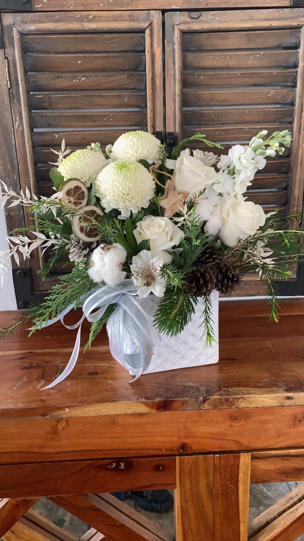 Peaceful holiday - White ceramic Vase with white flowers and Christmas Accents and decorations.
