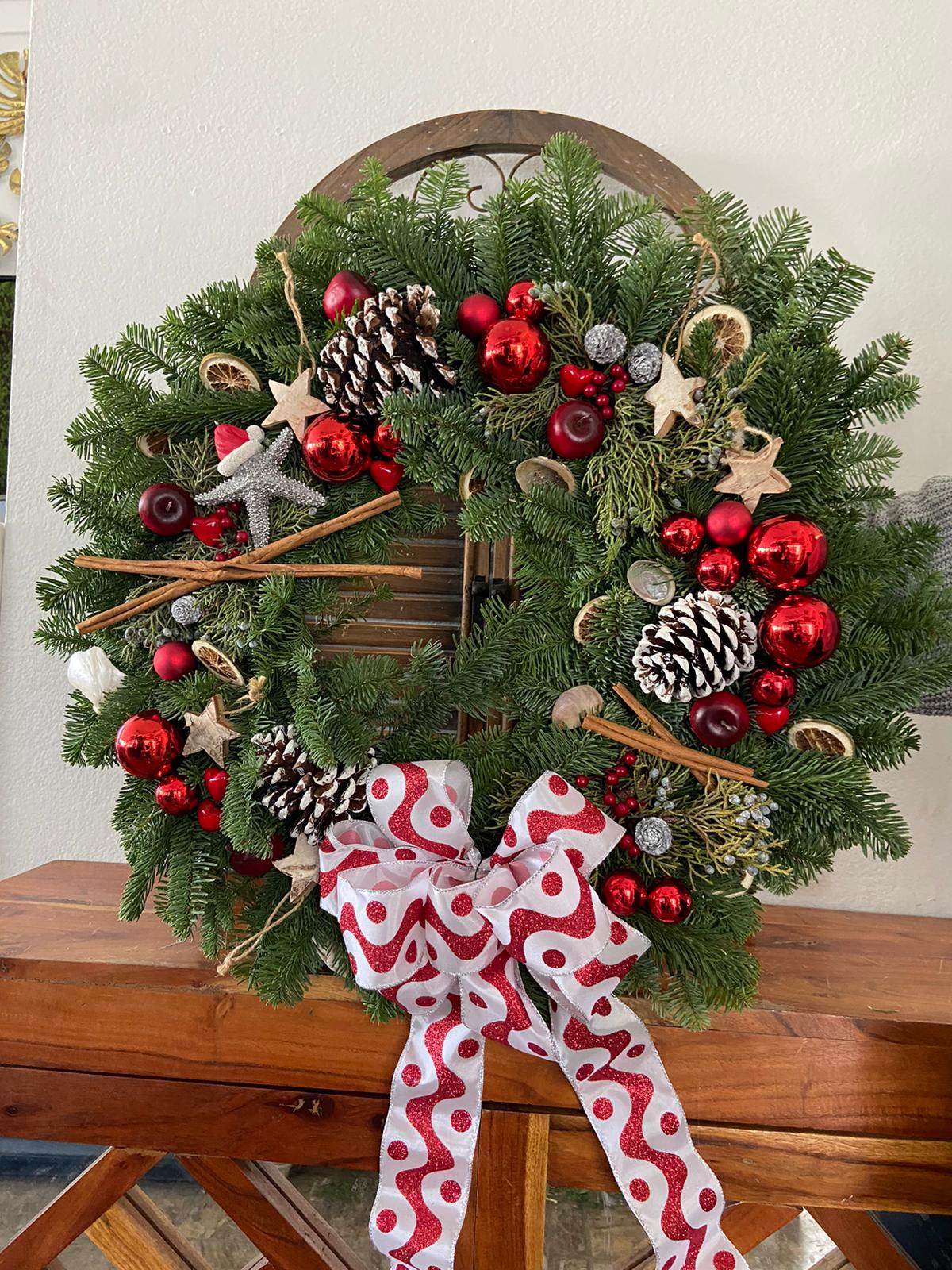 Christmas wreath with pinecones, red ornaments, and a patterned bow