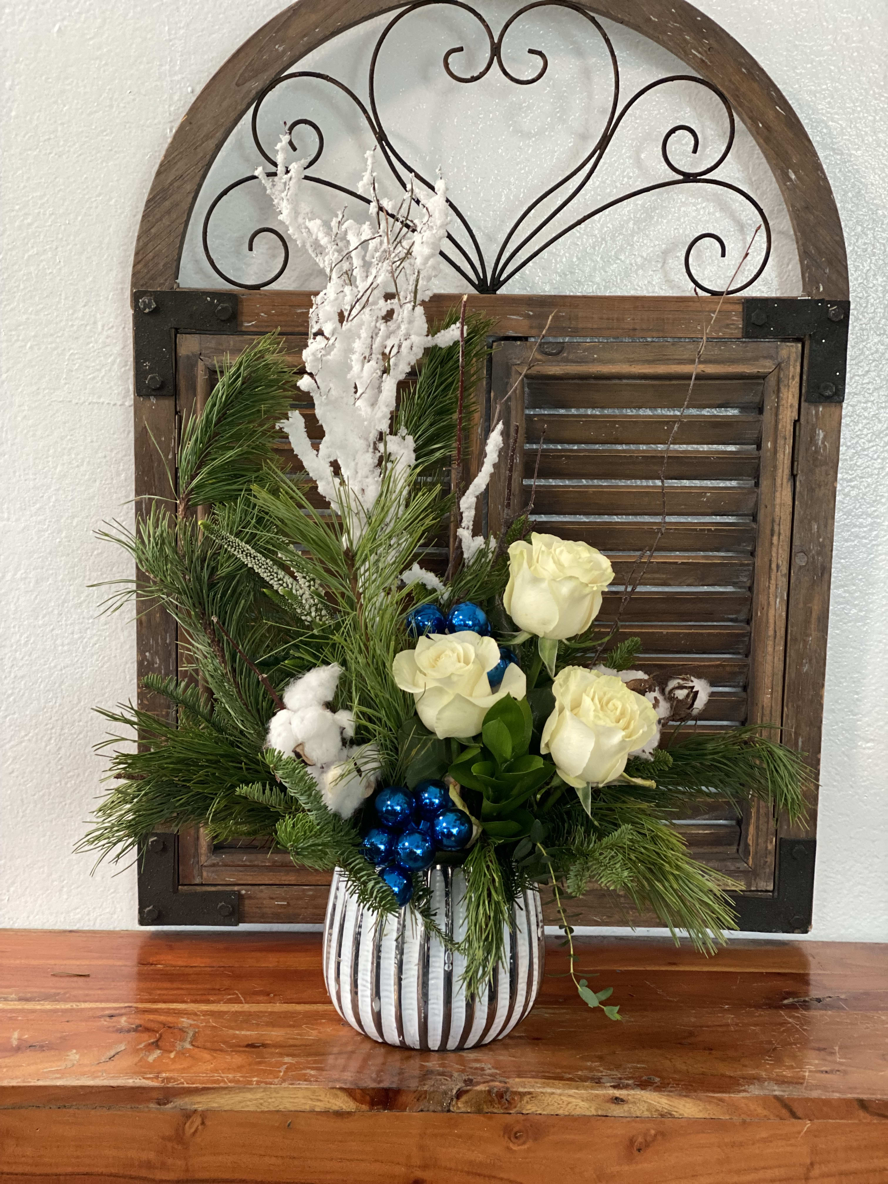 Holiday floral arrangement with white roses in a striped vase