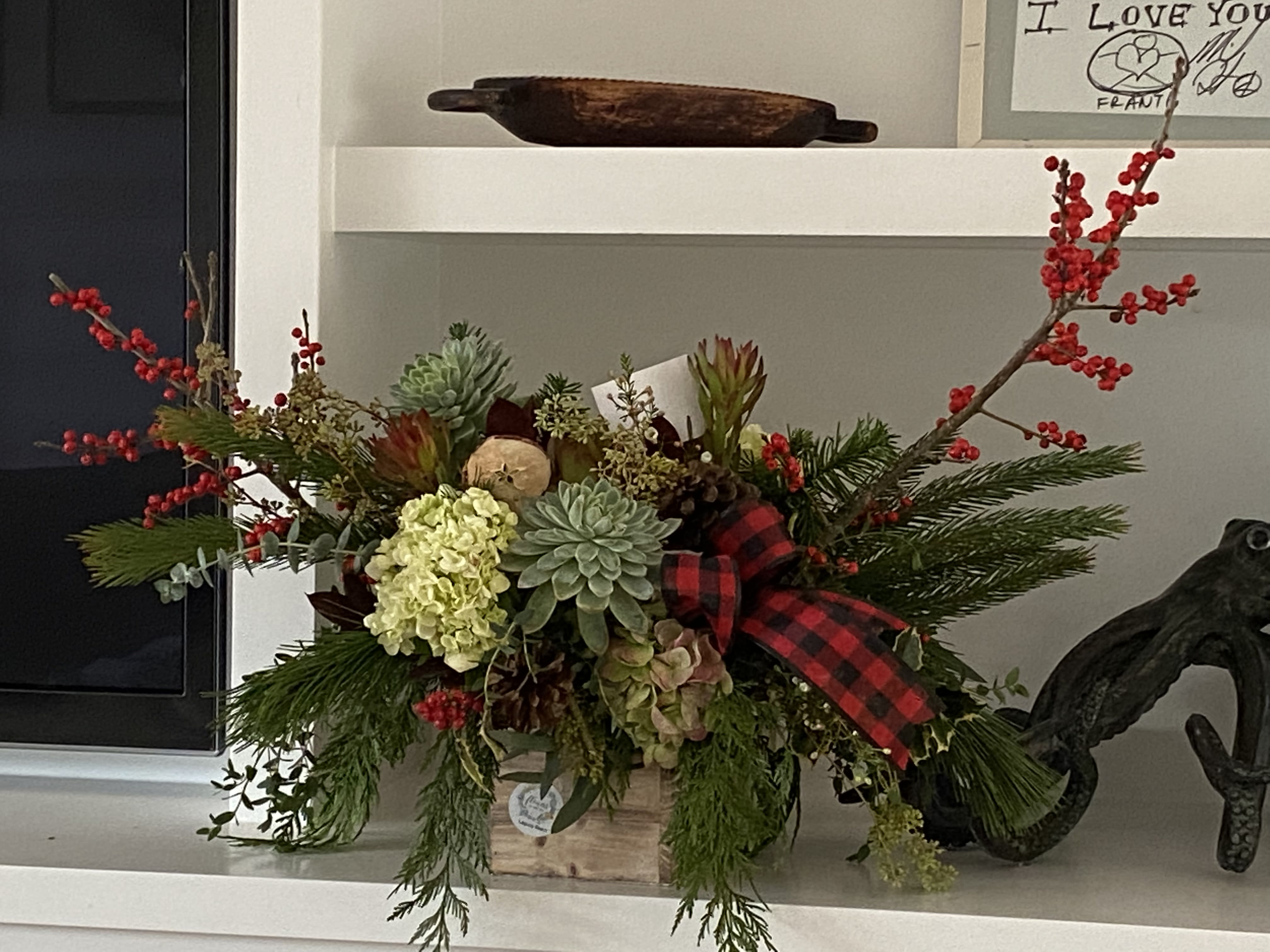 Holiday arrangement with succulents, hydrangea, and red berry branches in a wooden box