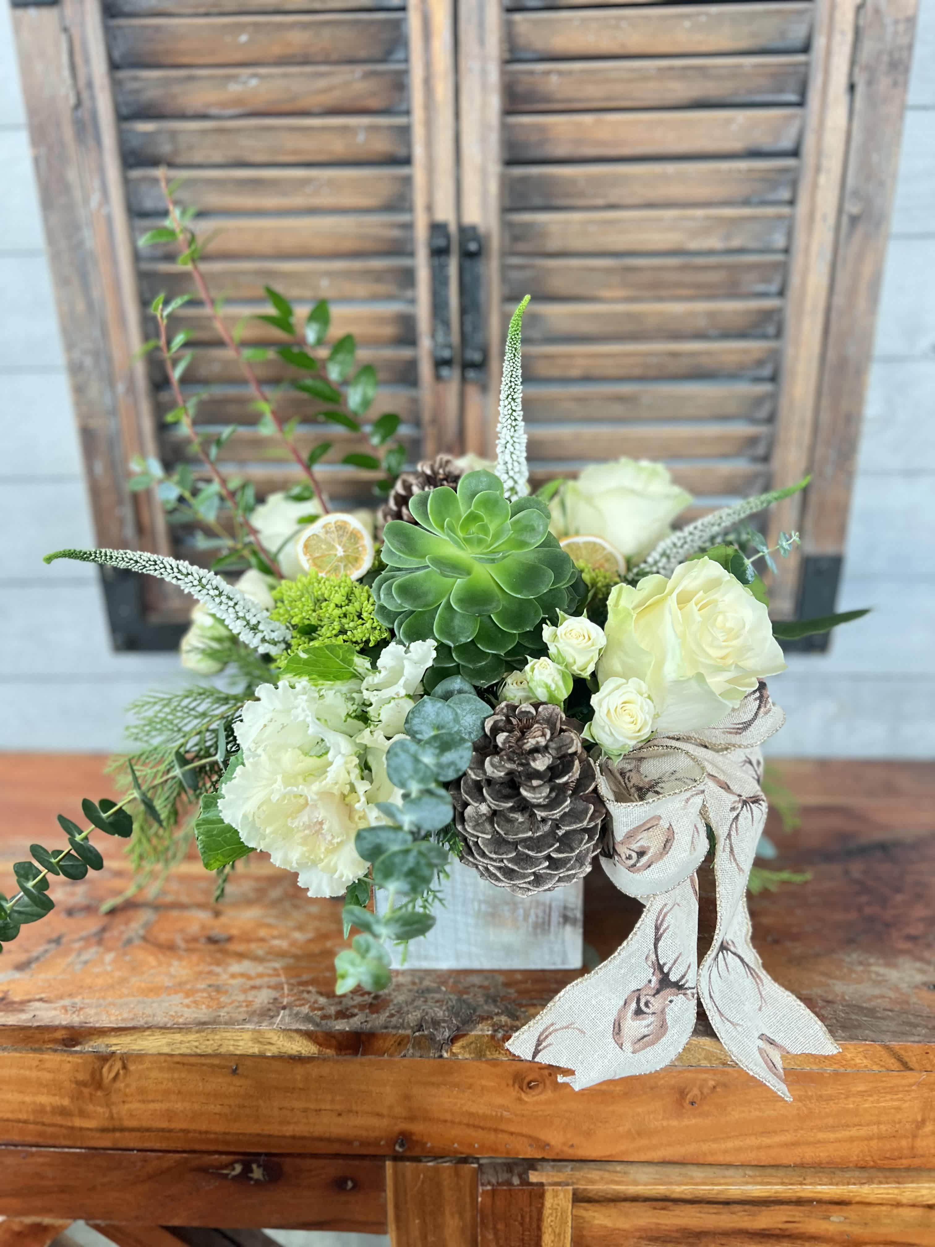 Succulent and white floral arrangement in a small box with pinecones and ribbon