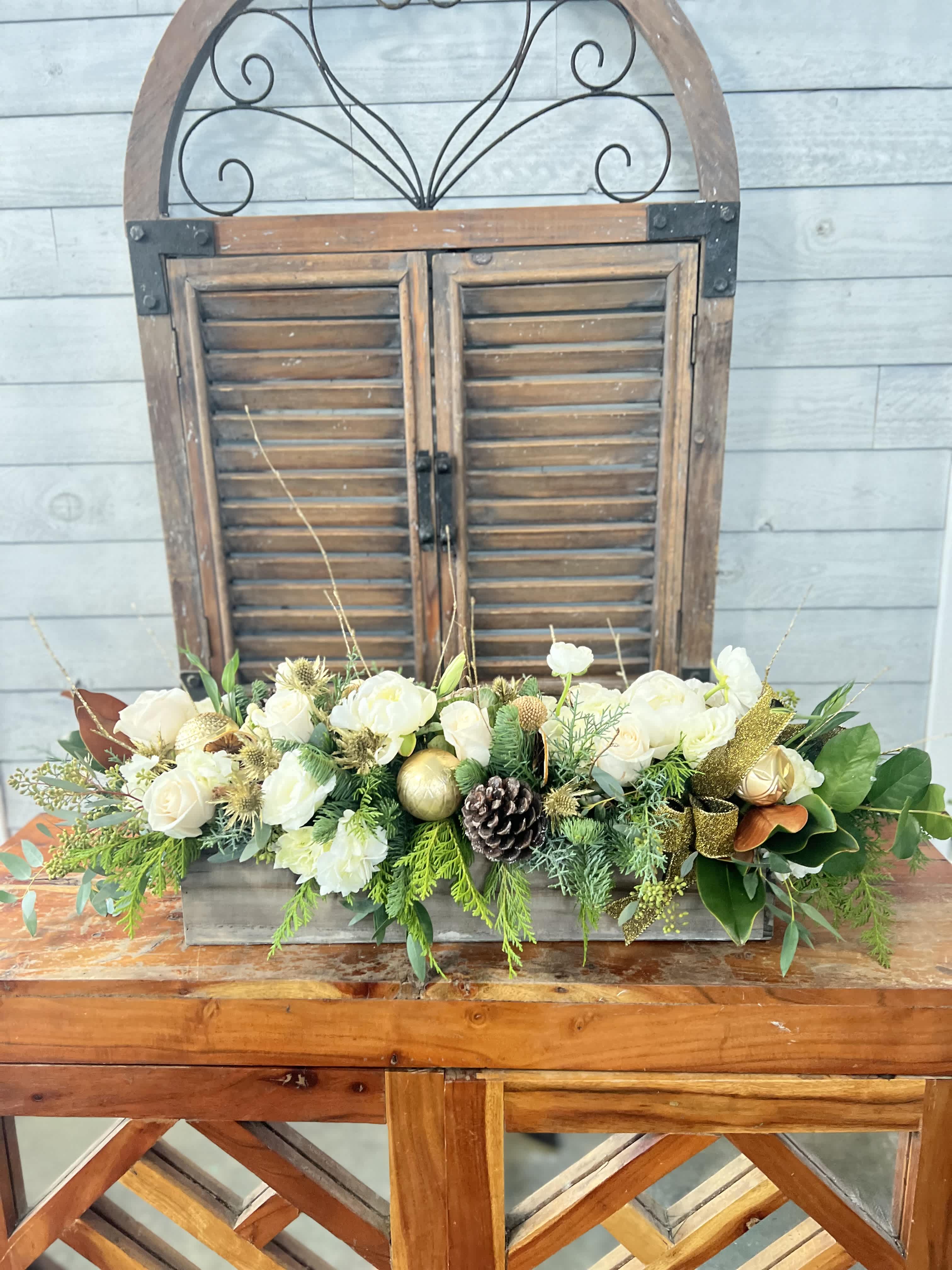White roses and greenery arranged in a rectangular wooden box with gold accents
