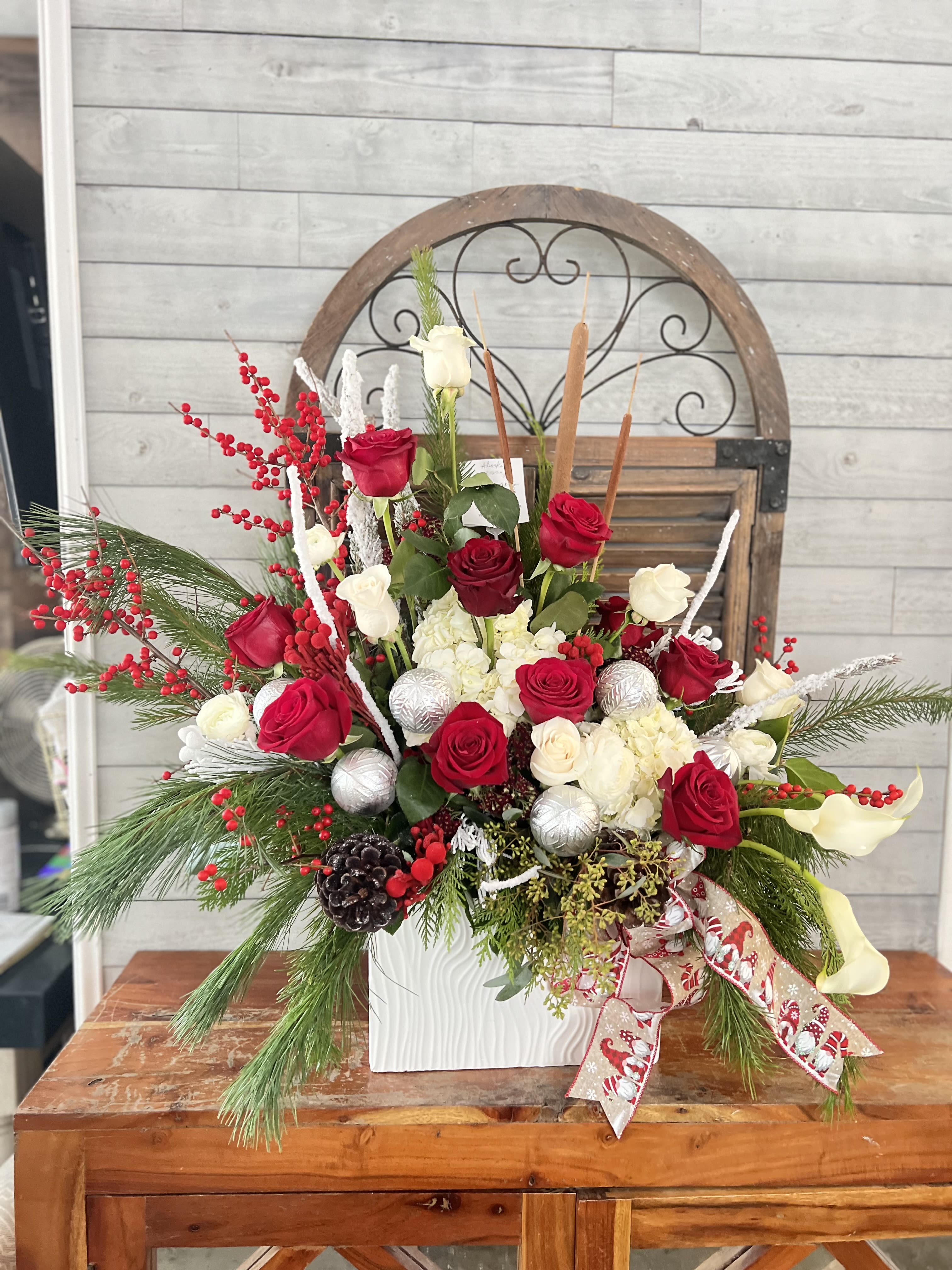 Holiday floral arrangement with red and white roses in a white vase