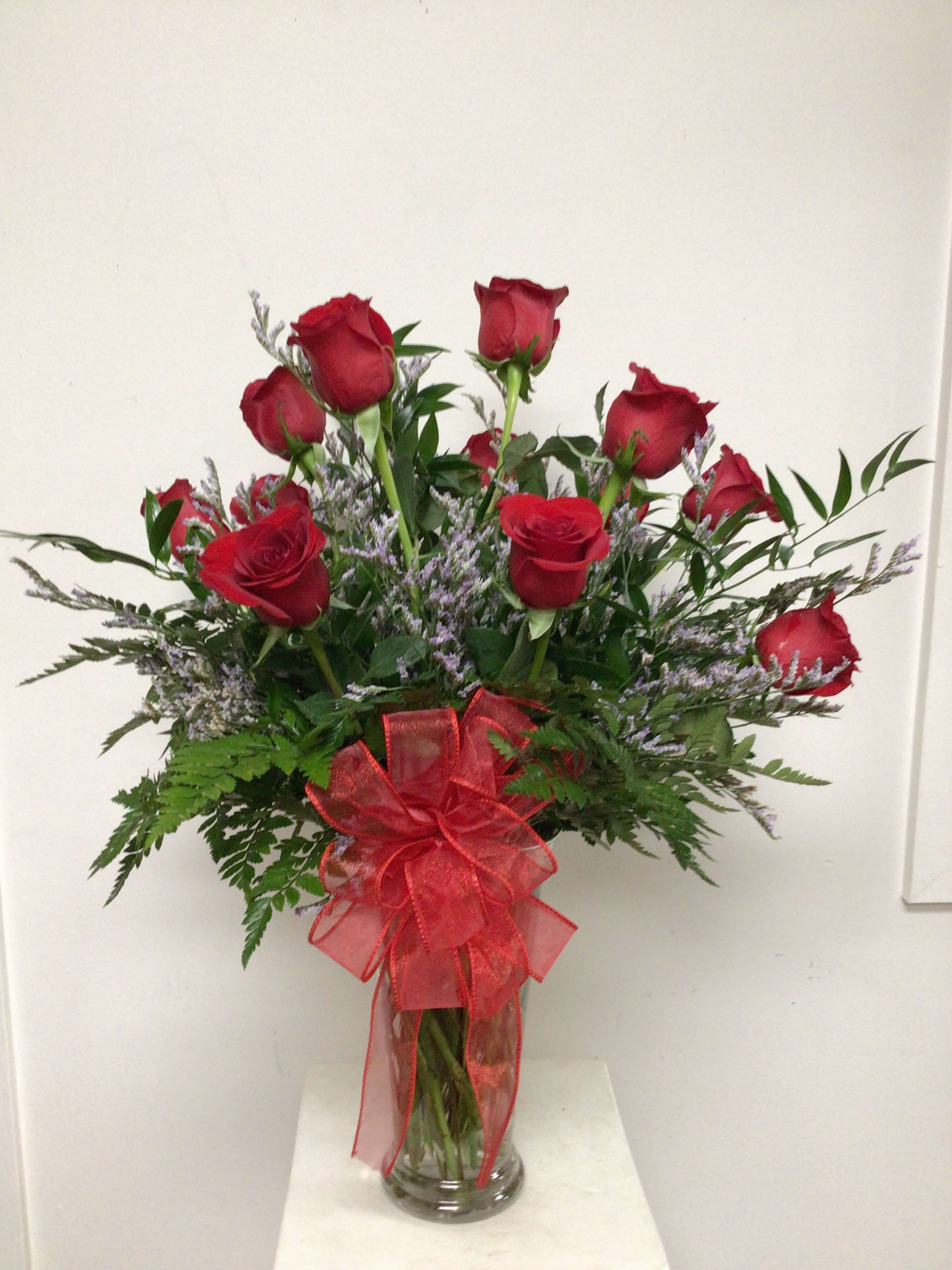 Red roses in a clear glass vase with a red ribbon bow