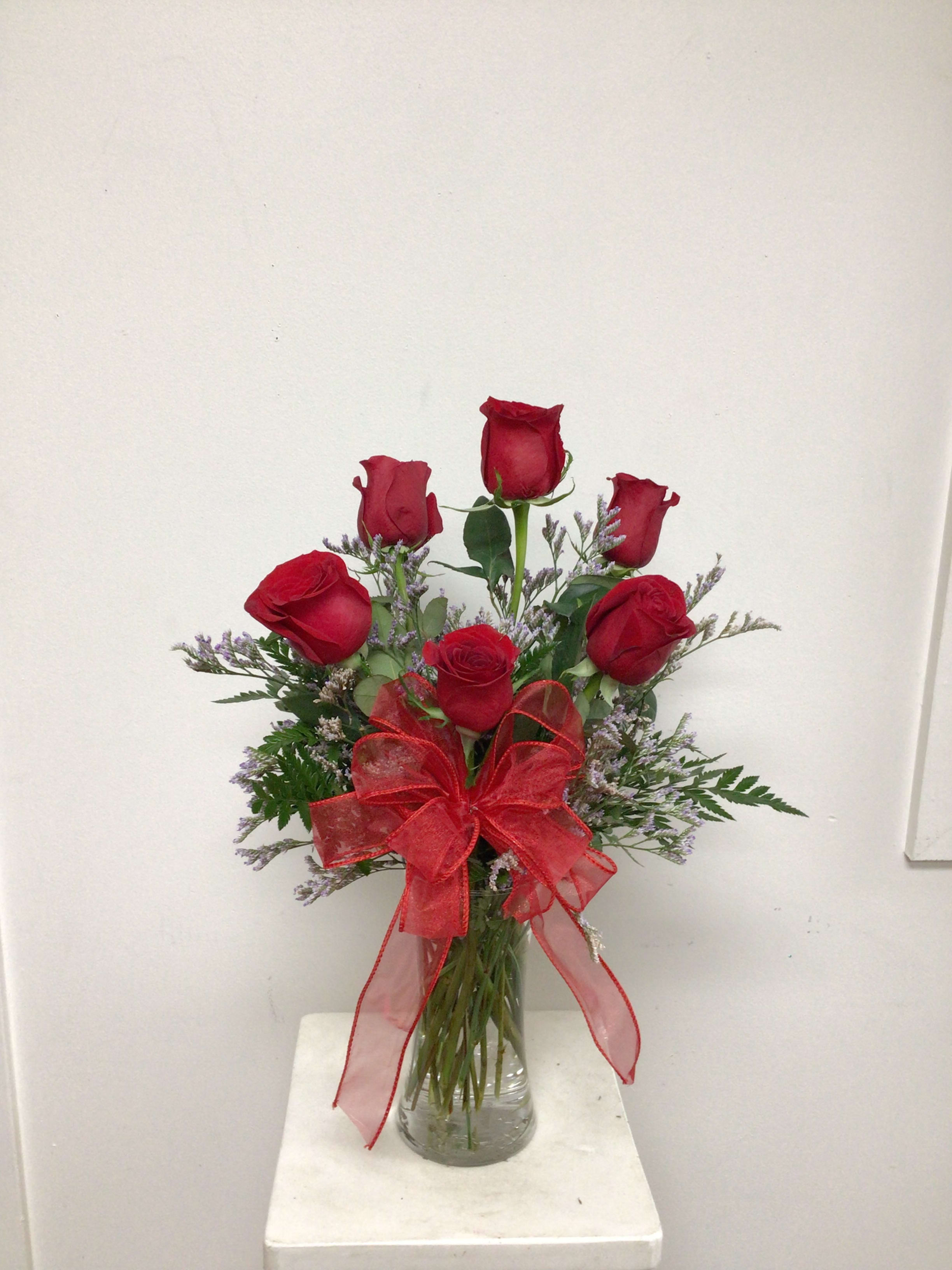 Red roses in a clear glass vase with a red ribbon bow