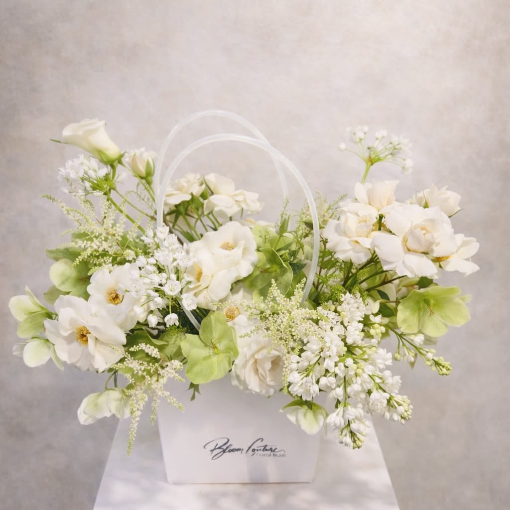 White Garden Couture - A fresh and elegant garden-style arrangement designed with premium seasonal flowers in soft white and green tones.  Featuring garden roses, hellebore, lilac, and delicate spring blossoms, this piece is arranged with natural movement and airy balance, creating a look that feels both refined and effortlessly organic.  Designed in the Bloom Couture signature box, this arrangement reflects the beauty of a blooming spring garden with a modern couture touch.  The soft color palette brings a sense of calm, freshness, and quiet luxury, making it perfect for birthdays, celebrations, sympathy, or simply bringing natural elegance into the home. 