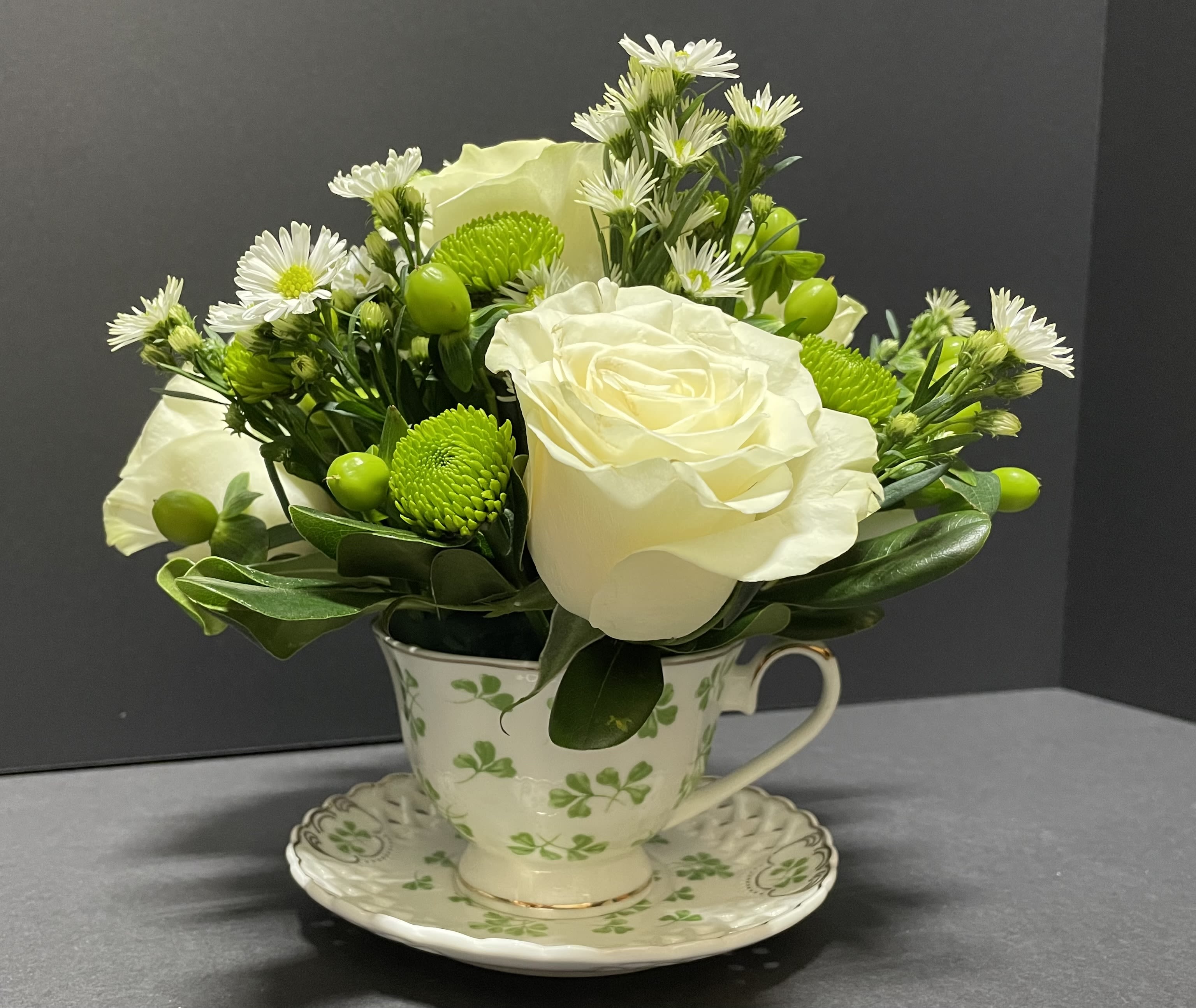 White roses and green button mums arranged in a teacup vase