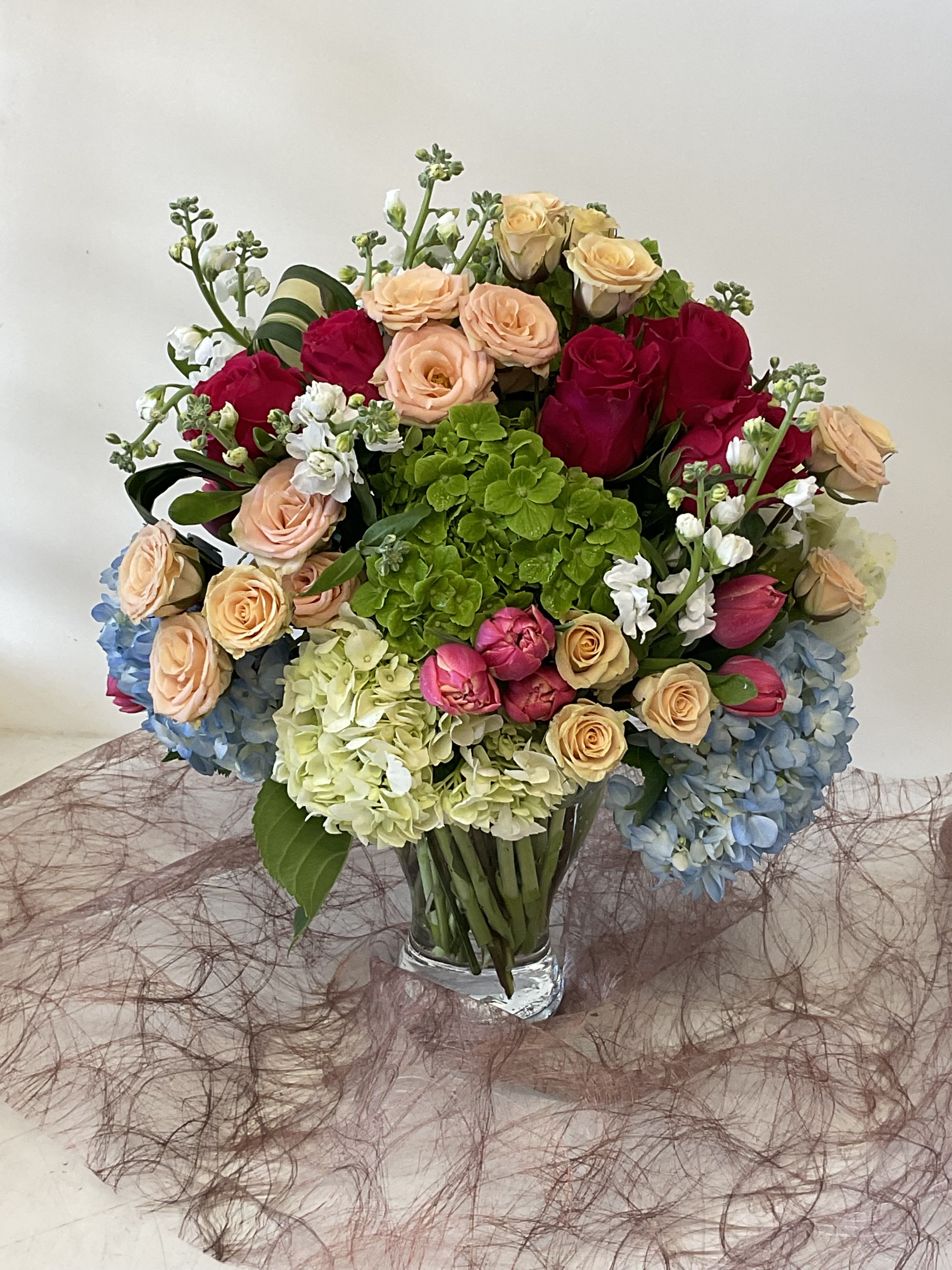 Mixed bouquet of roses and hydrangeas in a clear glass vase