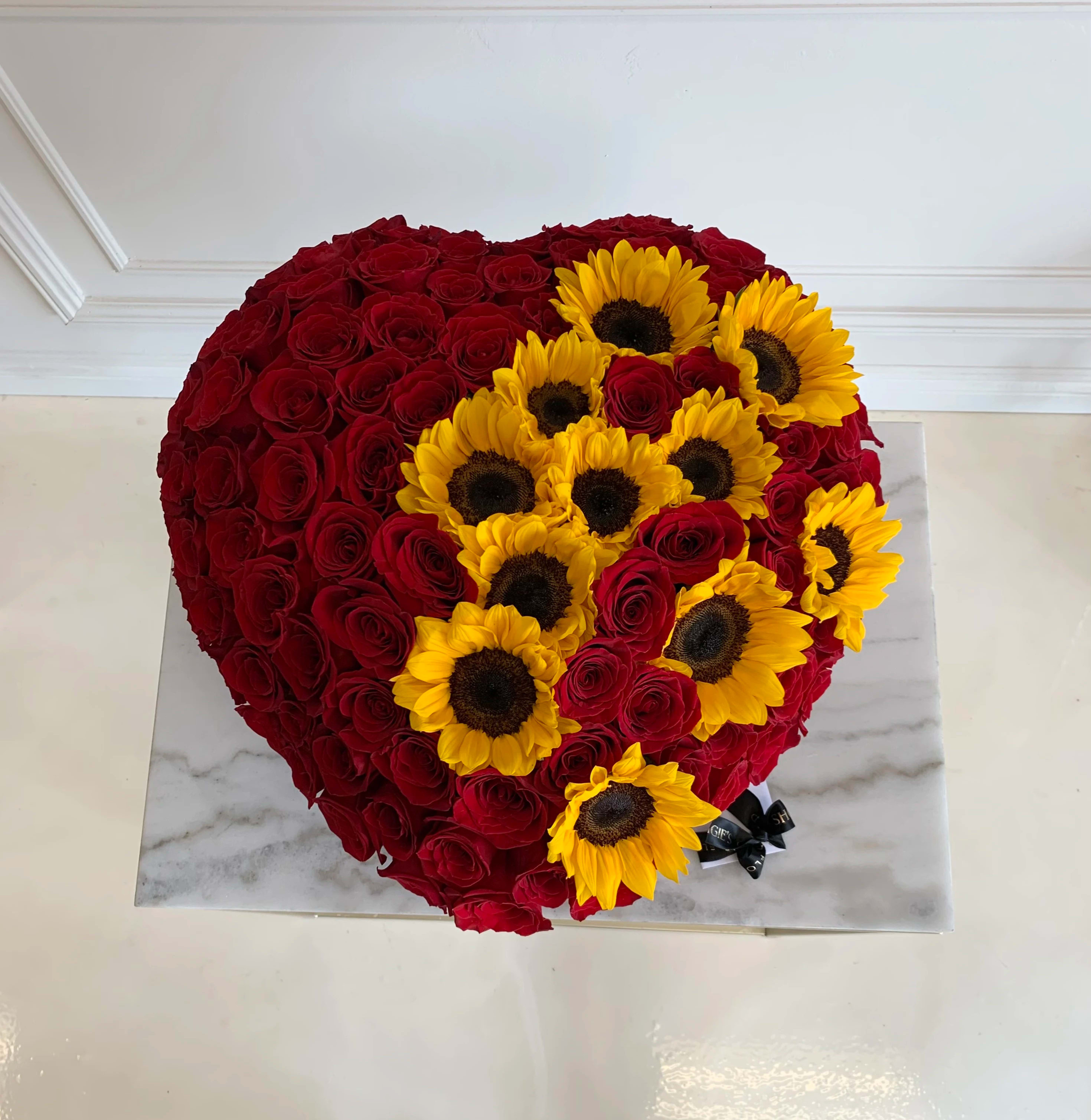 Heart-shaped arrangement of red roses with yellow sunflowers