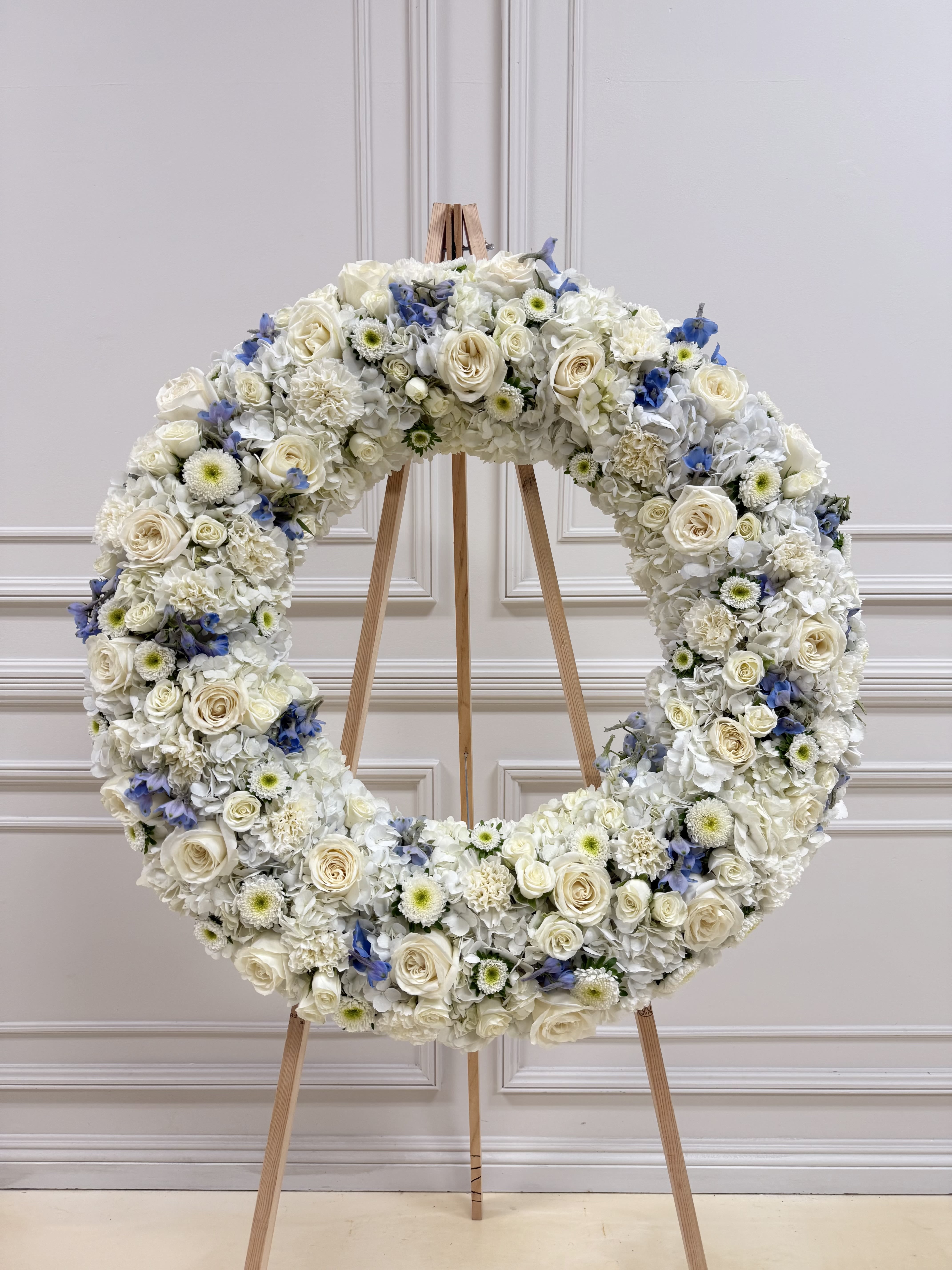 Large white floral wreath on a wooden easel