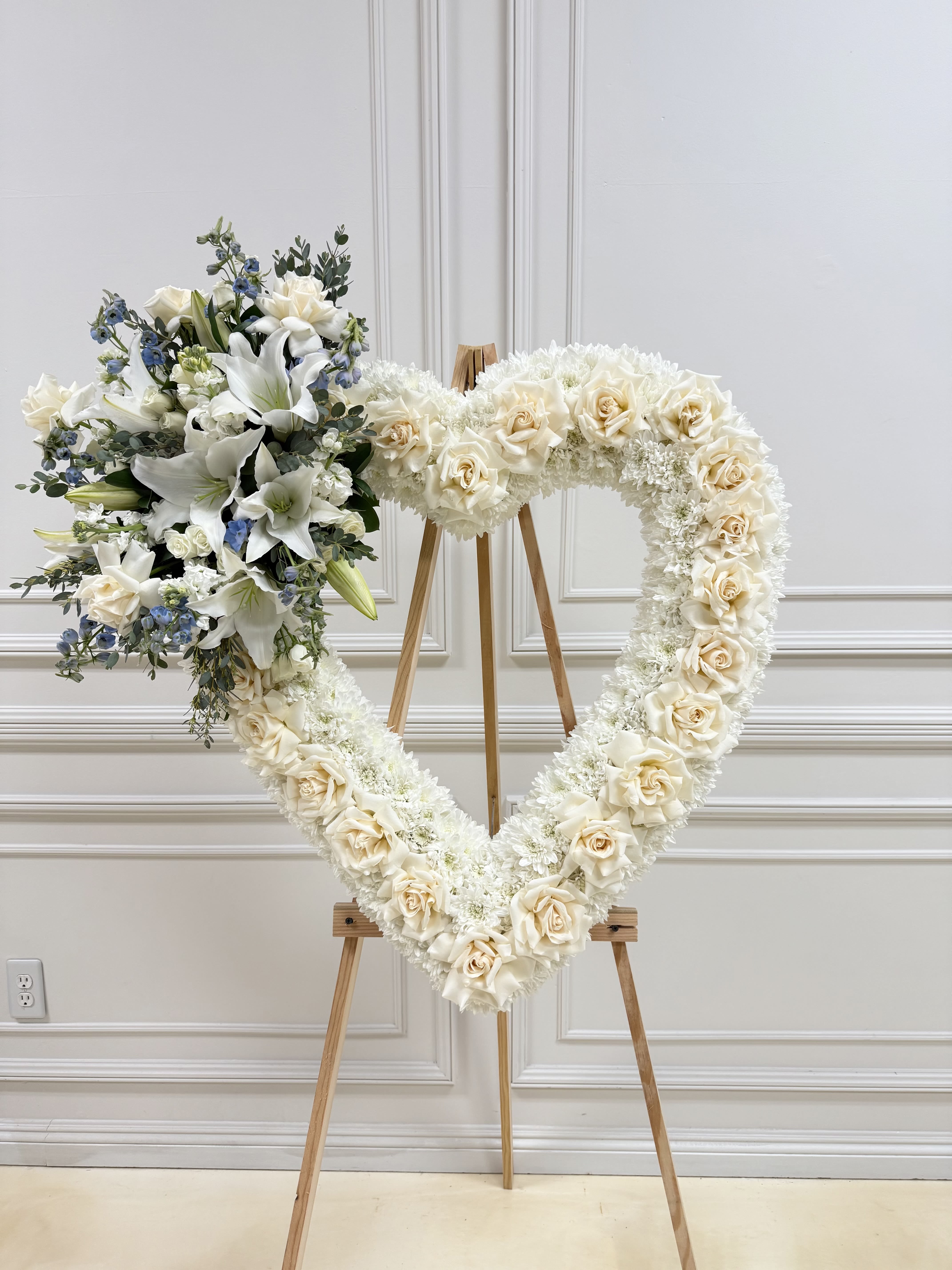 Heart-shaped floral wreath on an easel with white roses and lilies