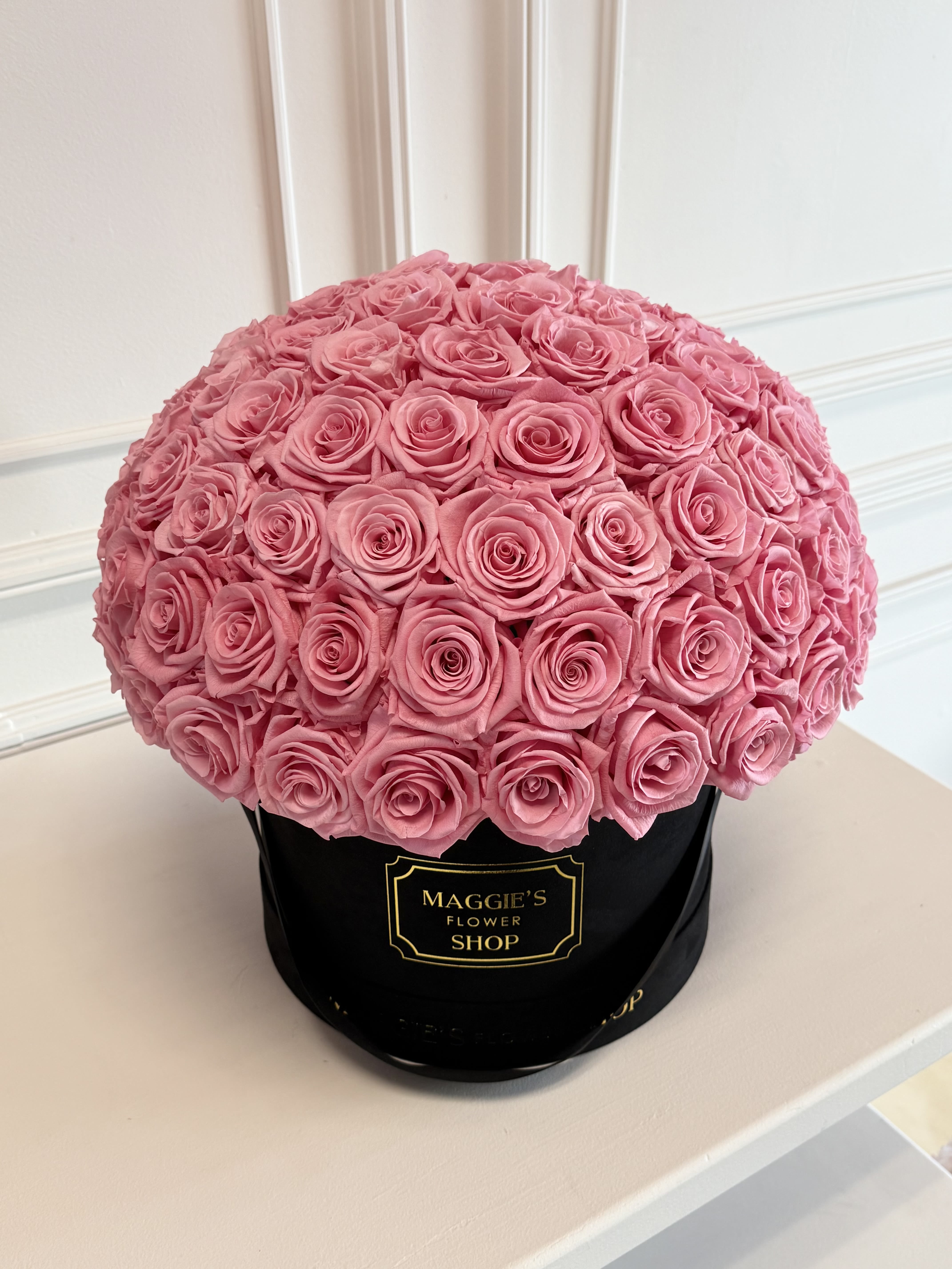 Round bouquet of pink roses in a black hat box