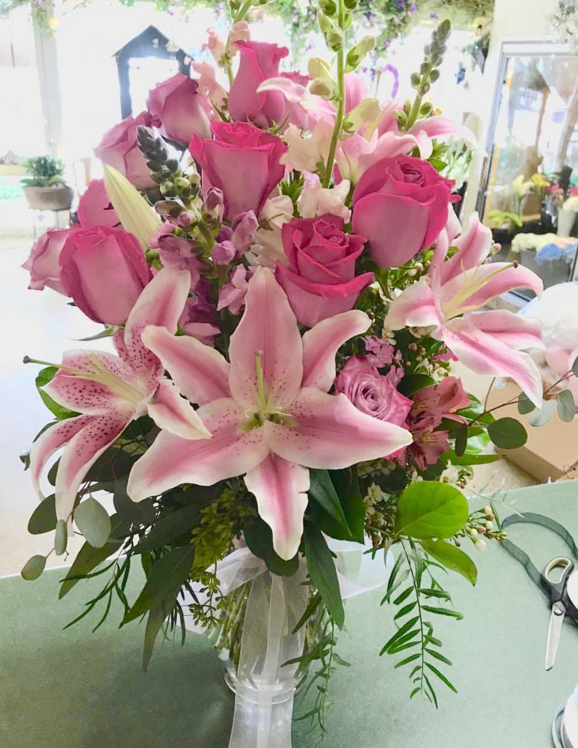 Pink roses and lilies arranged in a clear glass vase