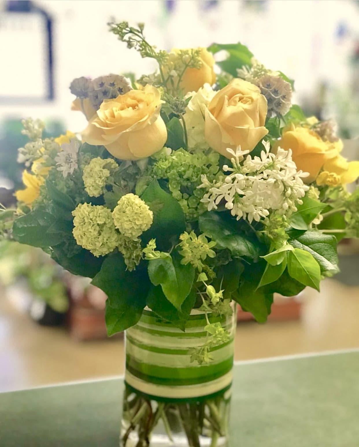Yellow roses and white filler flowers in a glass vase