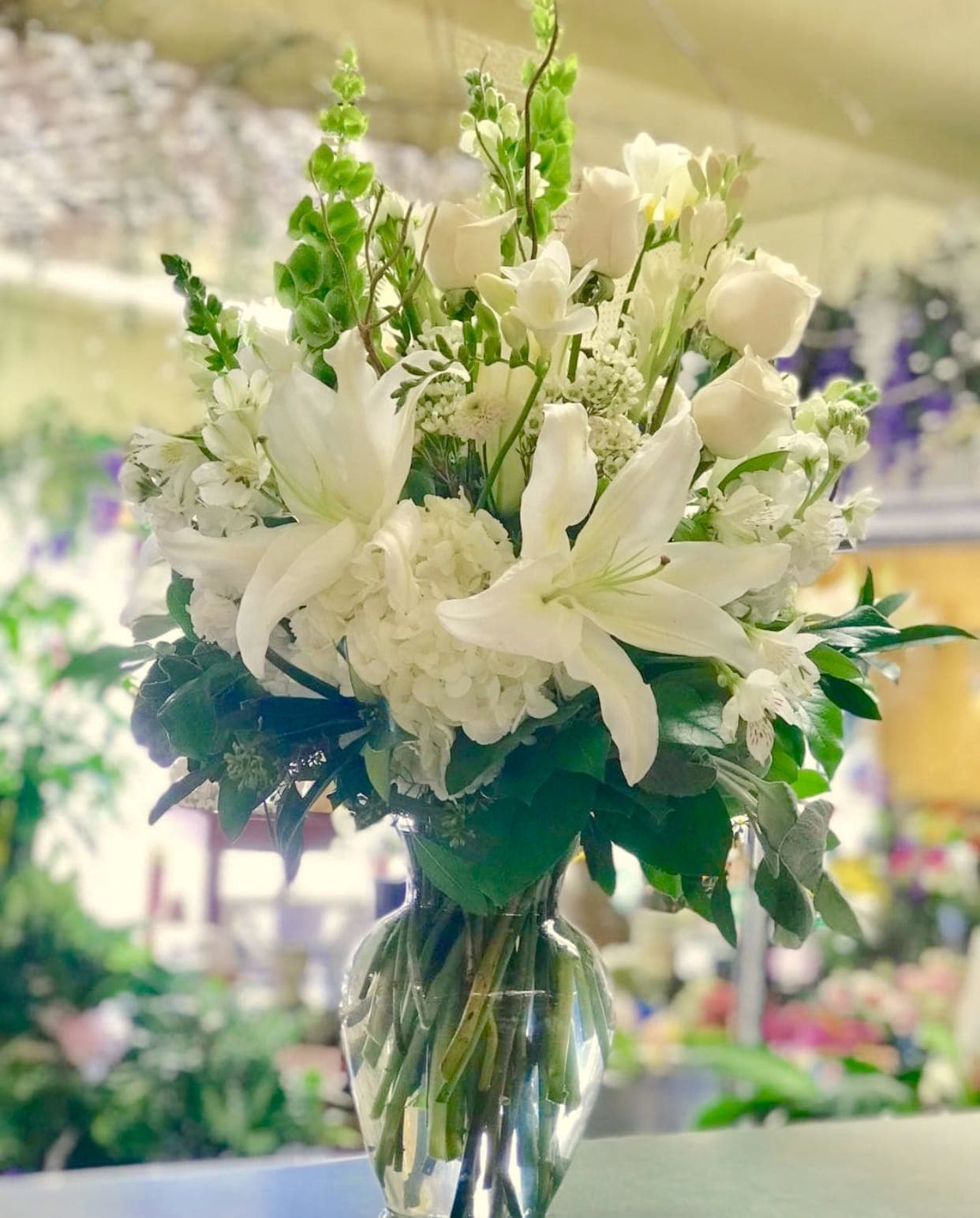 White lilies and roses arranged in a clear glass vase