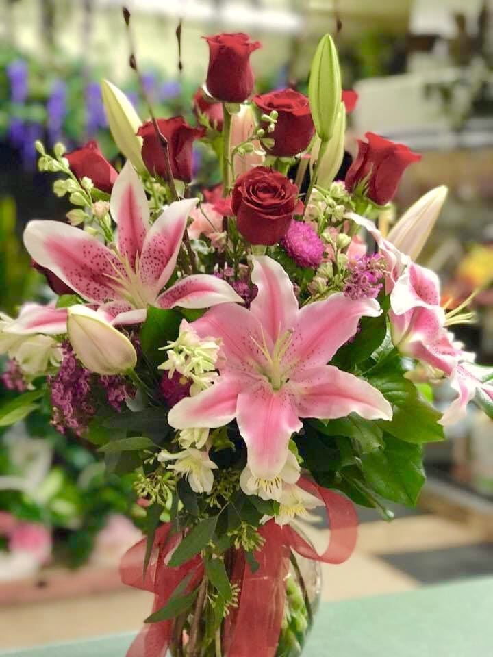 Bouquet of pink lilies and red roses tied with a ribbon