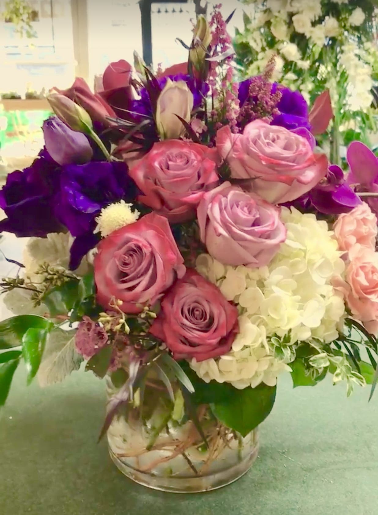 Bouquet of pink and purple roses with white hydrangea in a glass vase