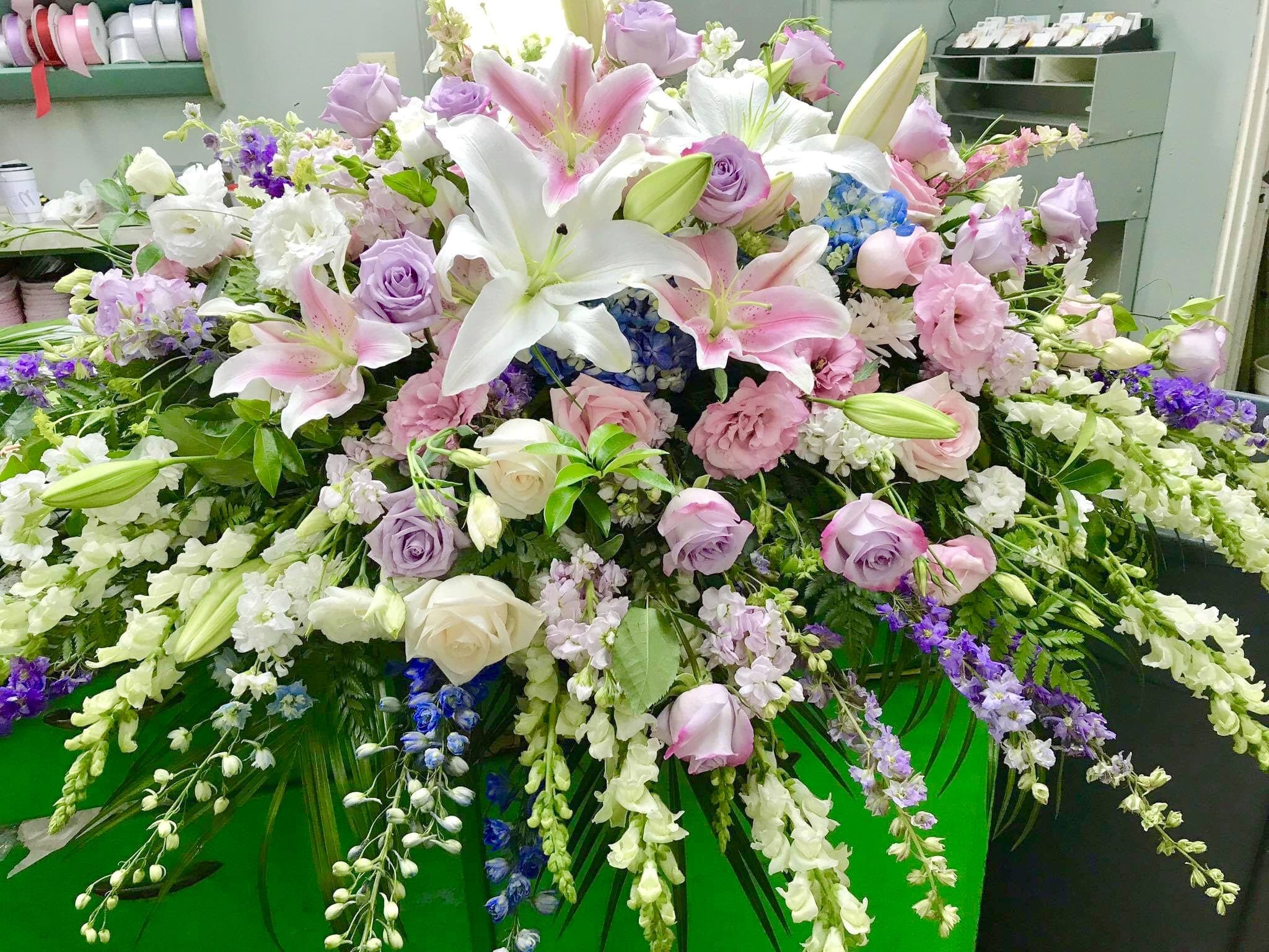 Large pastel floral arrangement with lilies, roses, and cascading blooms
