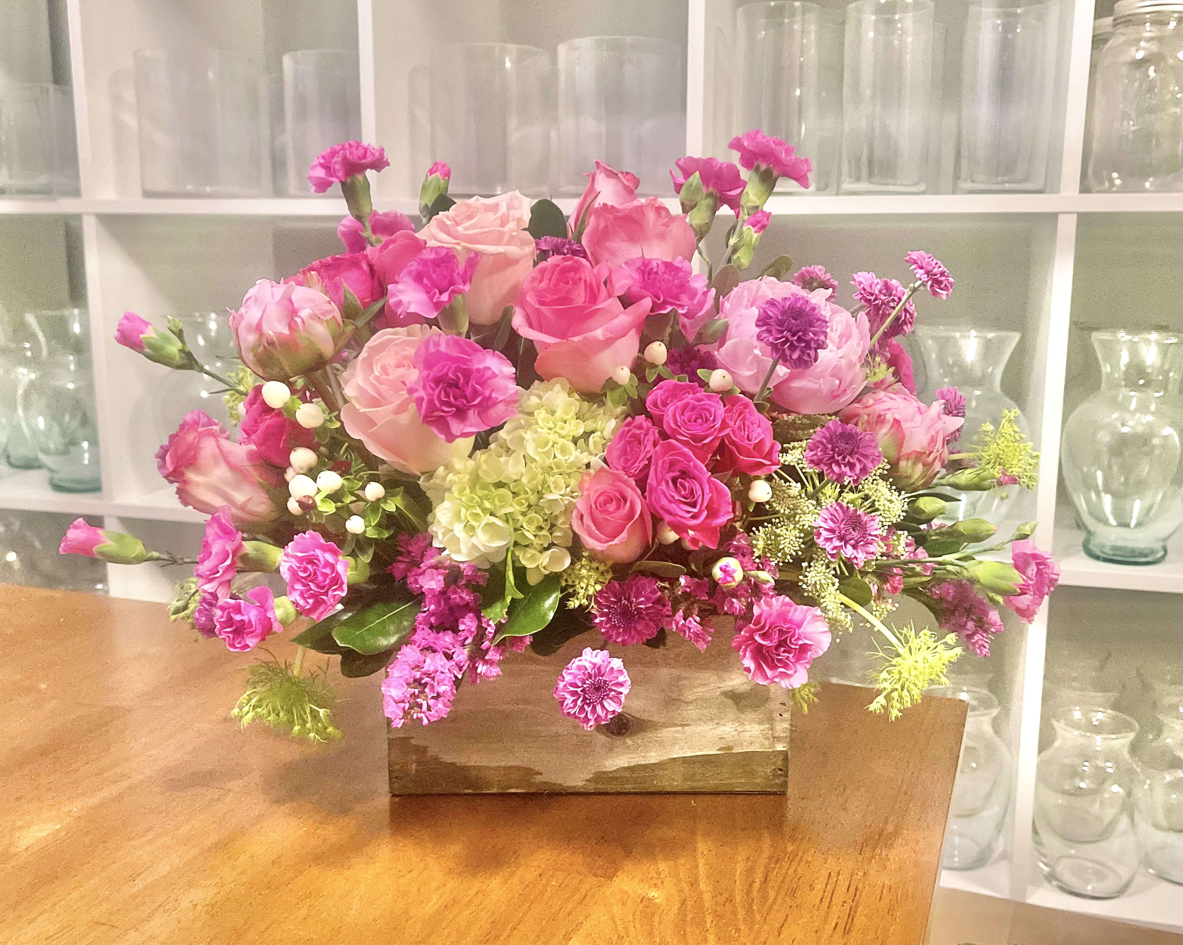 Pink and peach floral arrangement in a wooden box