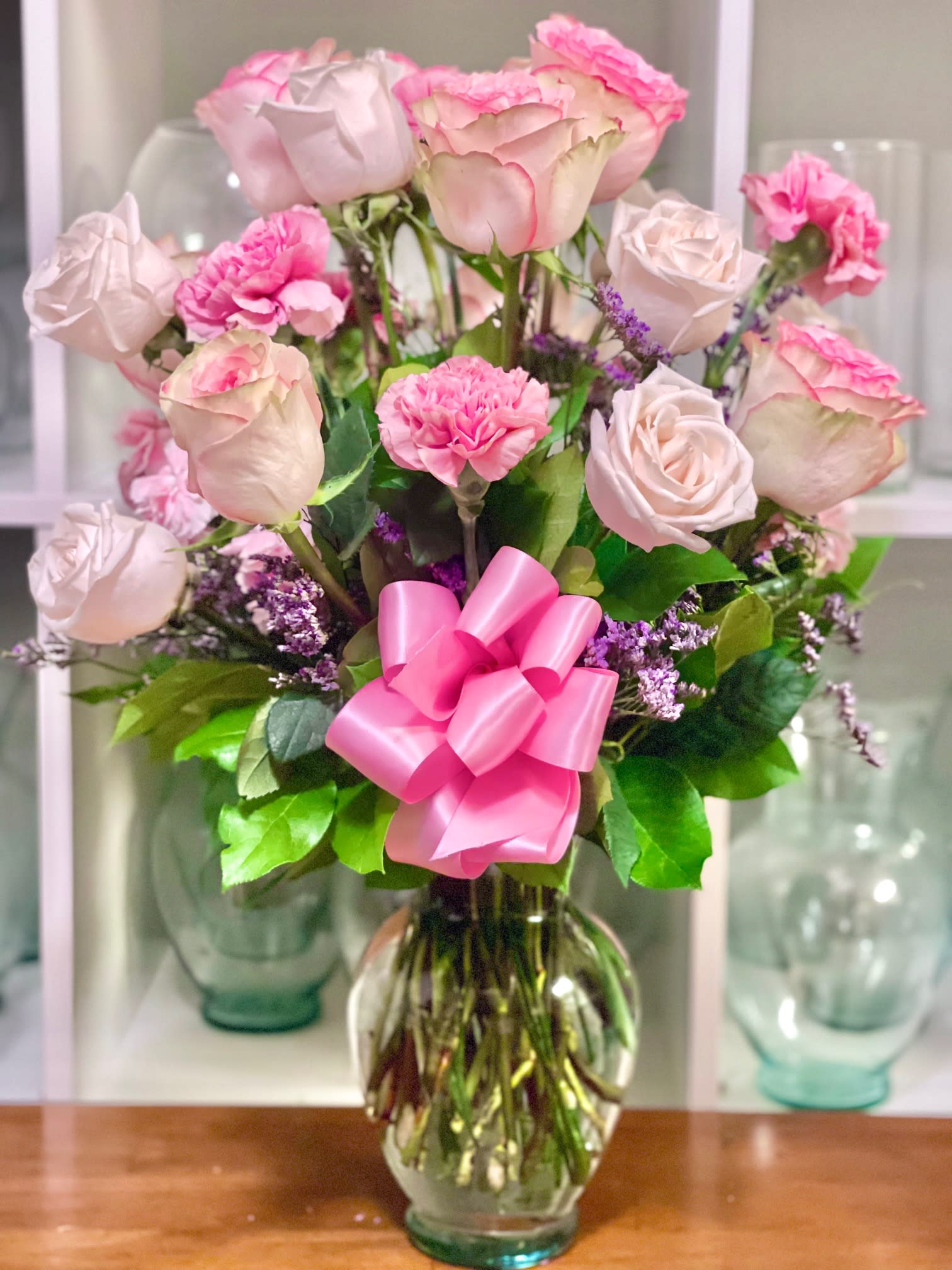 Pink roses and carnations in a glass vase with a pink ribbon