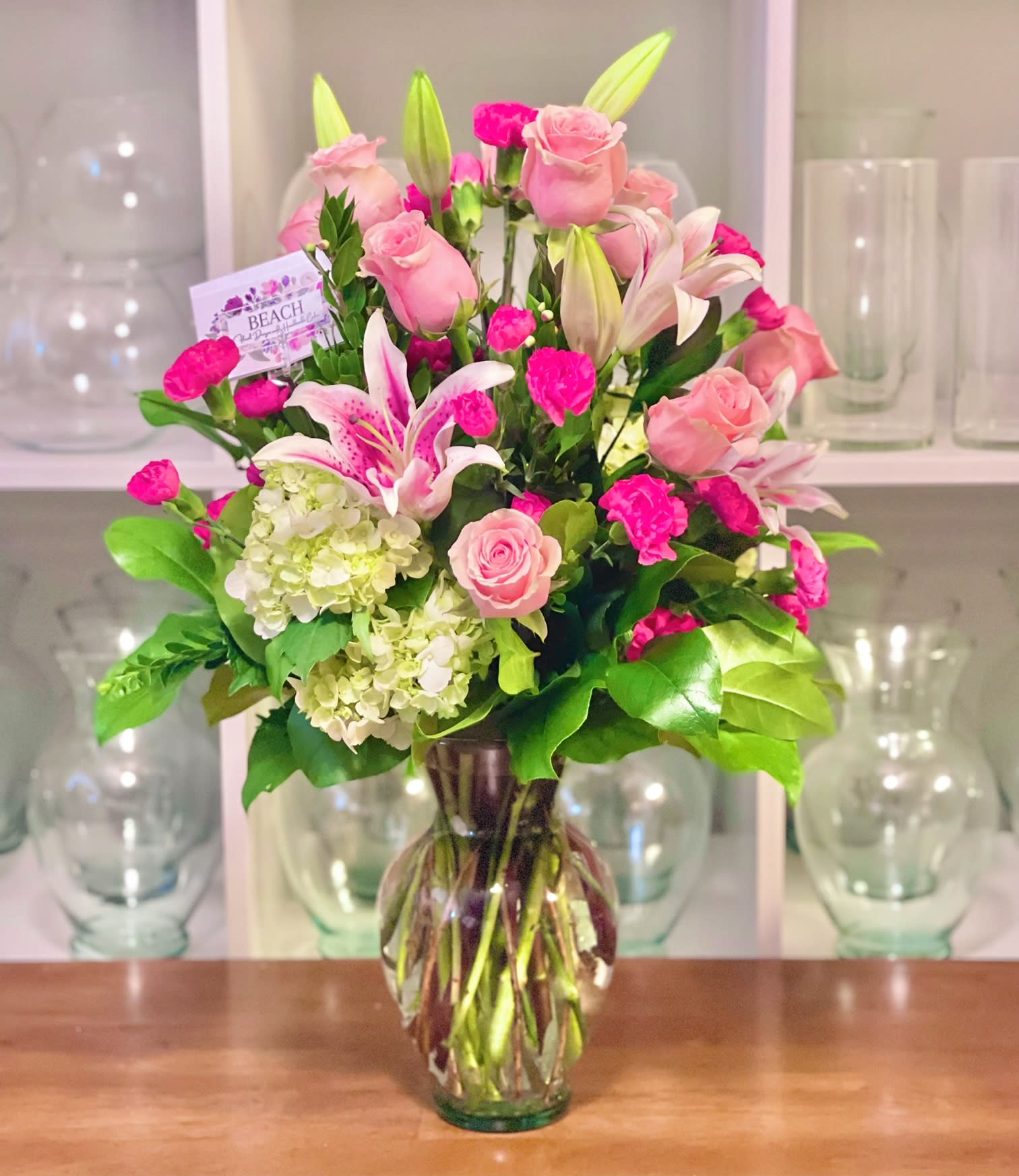 Pink roses and lilies arranged in a clear glass vase