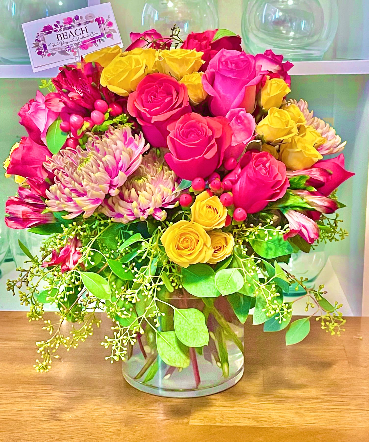 Oooo LaLa - A vibrant and unique arrangement of premium seasonal flowers including roses, mini psray roses, chrysanthemums, alstroemeria, mini carnations and berries accented with seeded eucalyptus and in a clear 6.5" cylinder vase. 