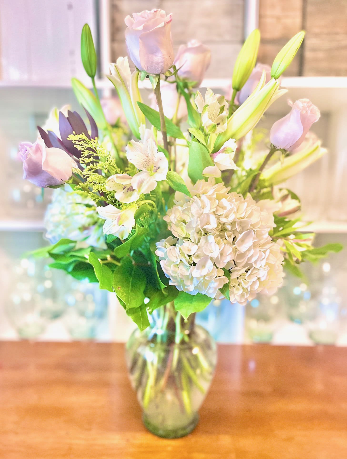 Pastel bouquet of roses, lilies, and hydrangeas in a glass vase