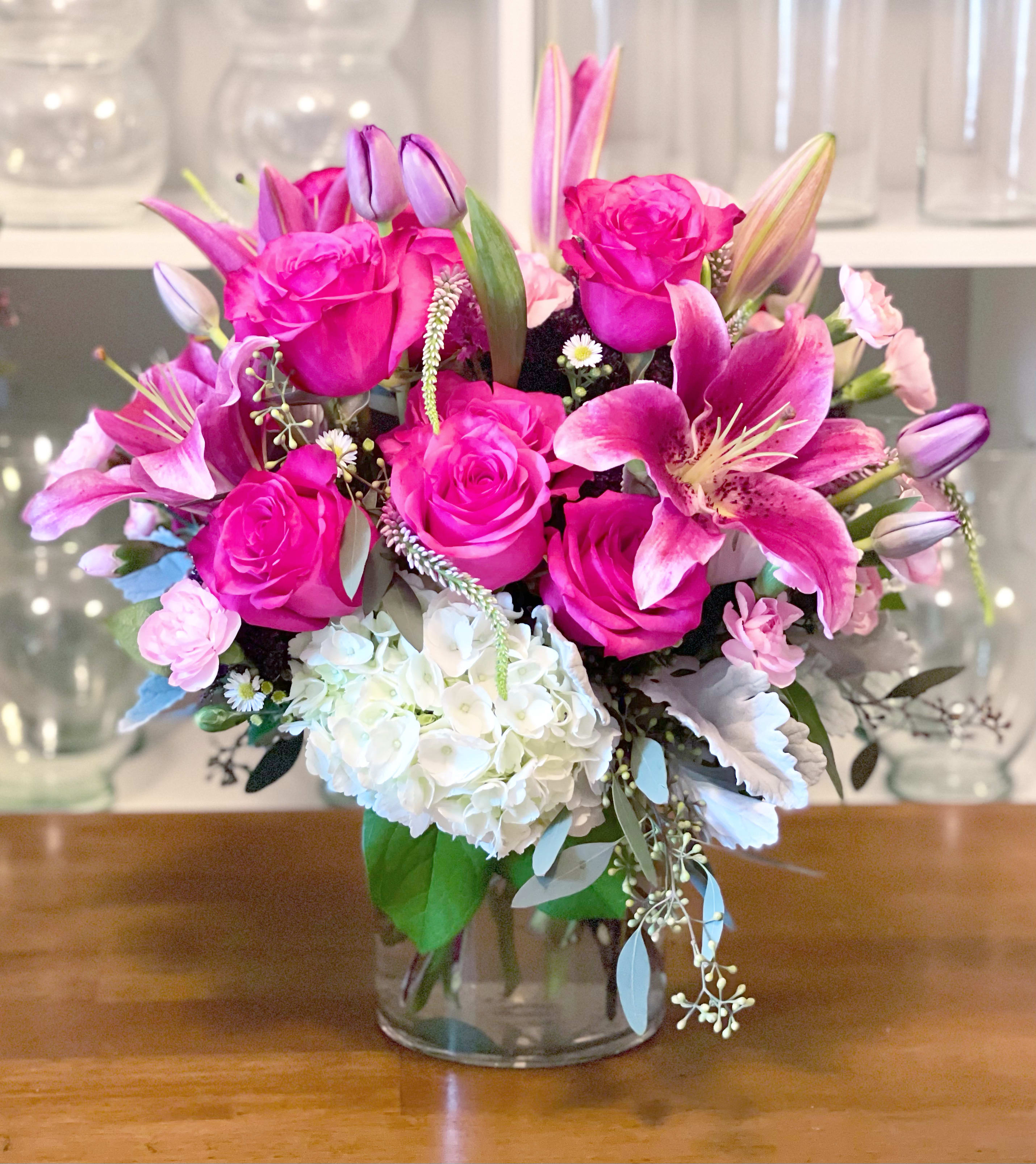 Pink roses and lilies arranged with white hydrangea in a glass vase