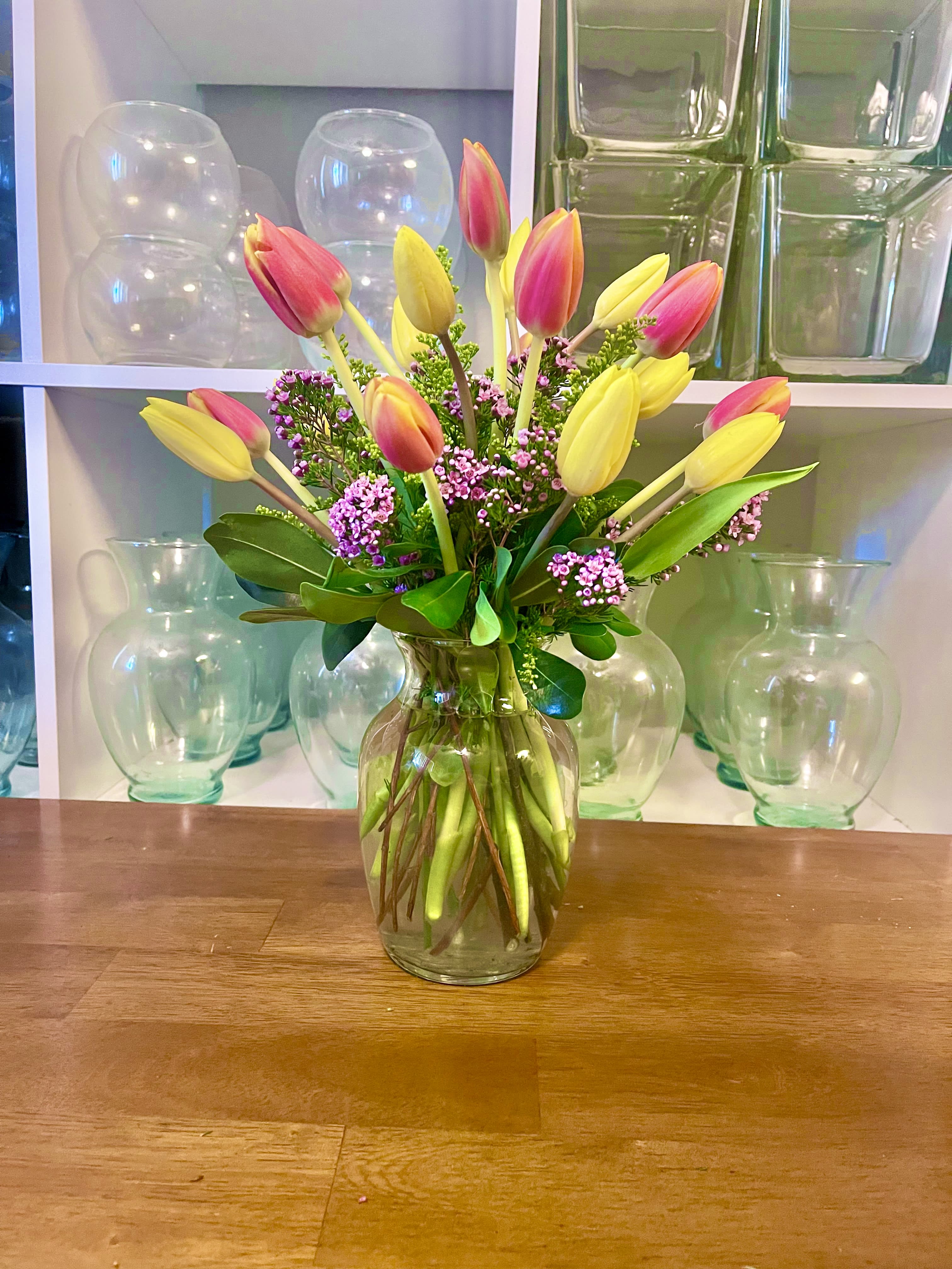 Pink and yellow tulips arranged in a clear glass vase