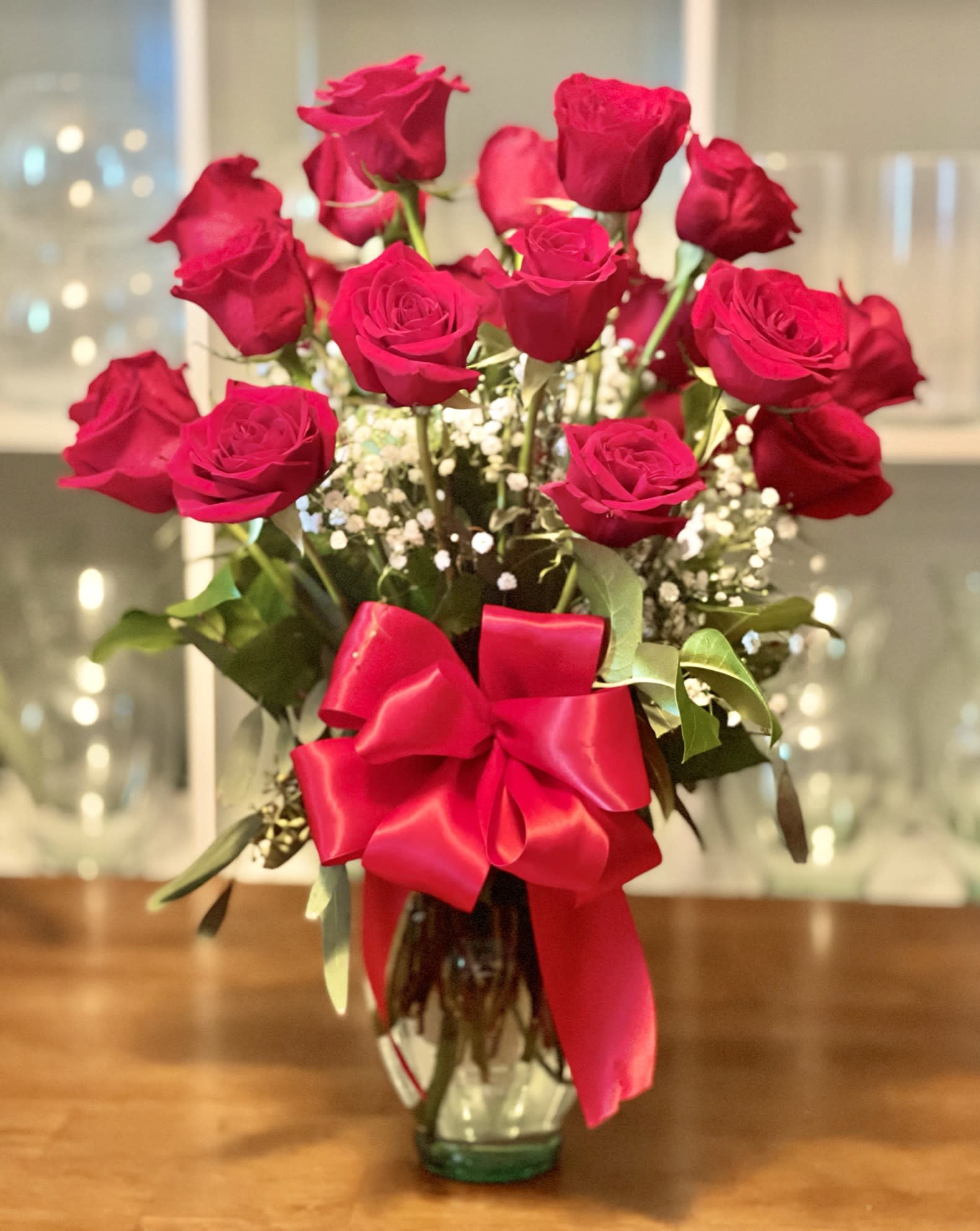 Bouquet of red roses in a glass vase with a large red ribbon