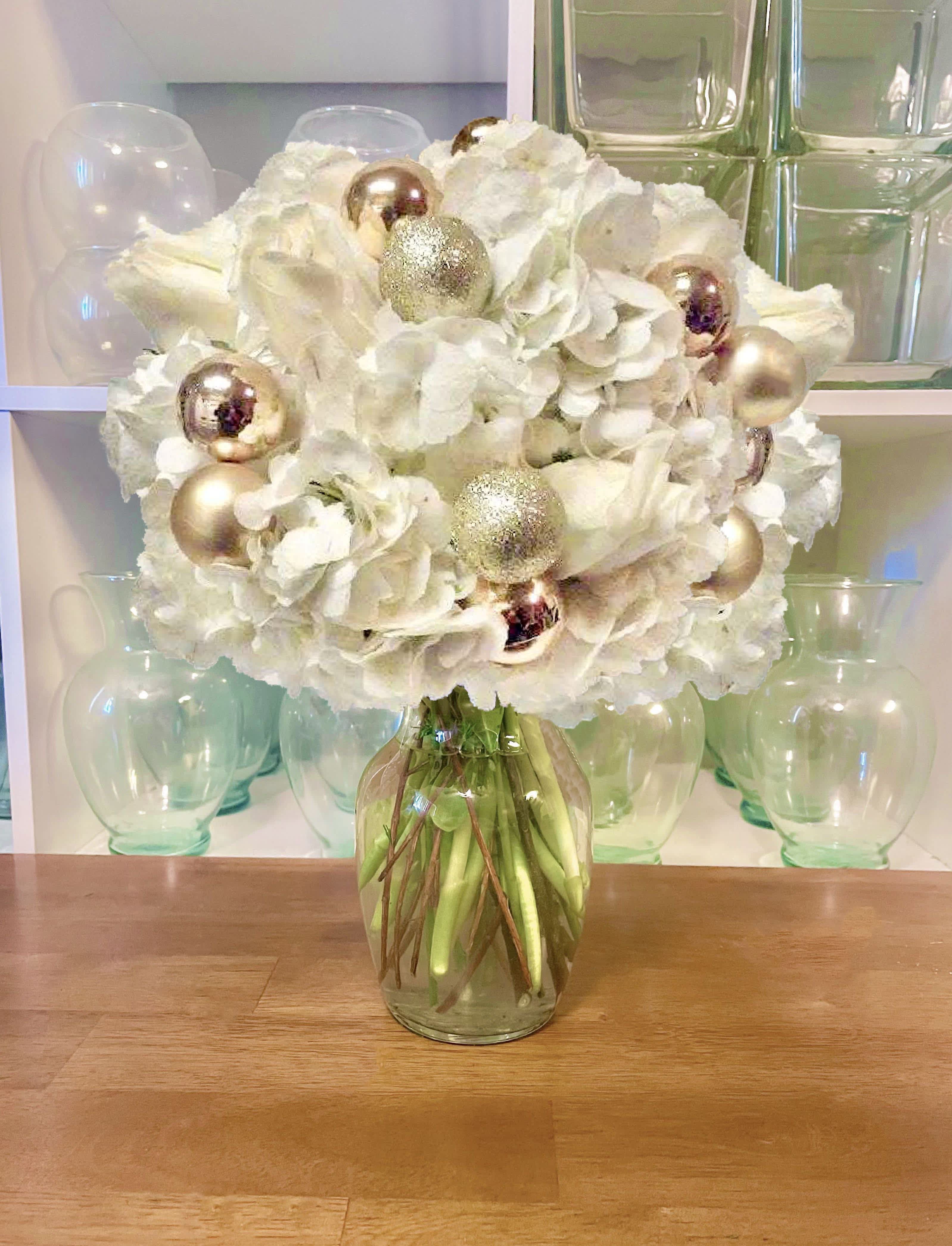 Winter Wonderland - Stunning white Hydrangea and Premium white Roses  accented with festive ornaments in a clear glass vase.