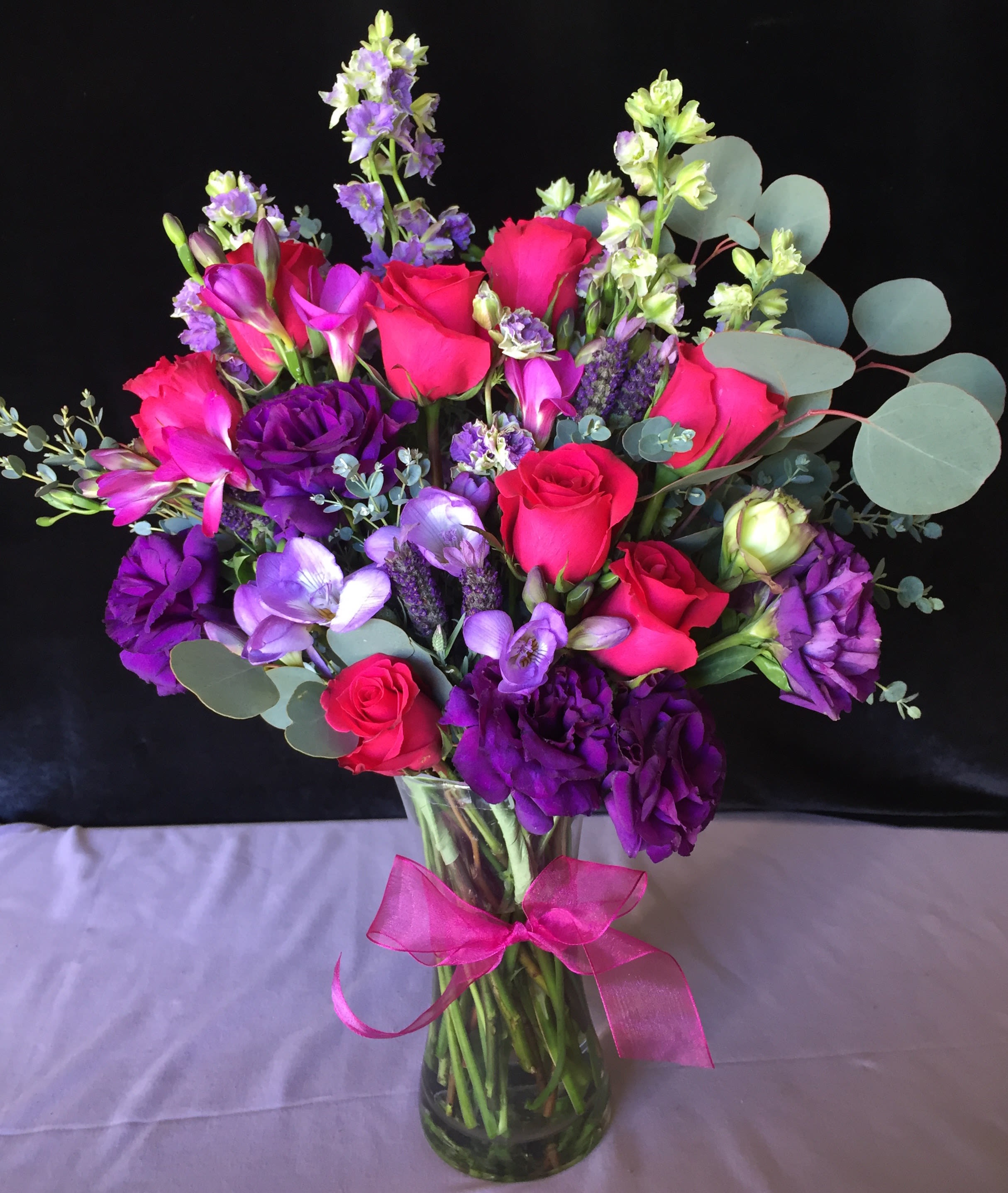 Bouquet of pink and purple flowers in a glass vase with a ribbon