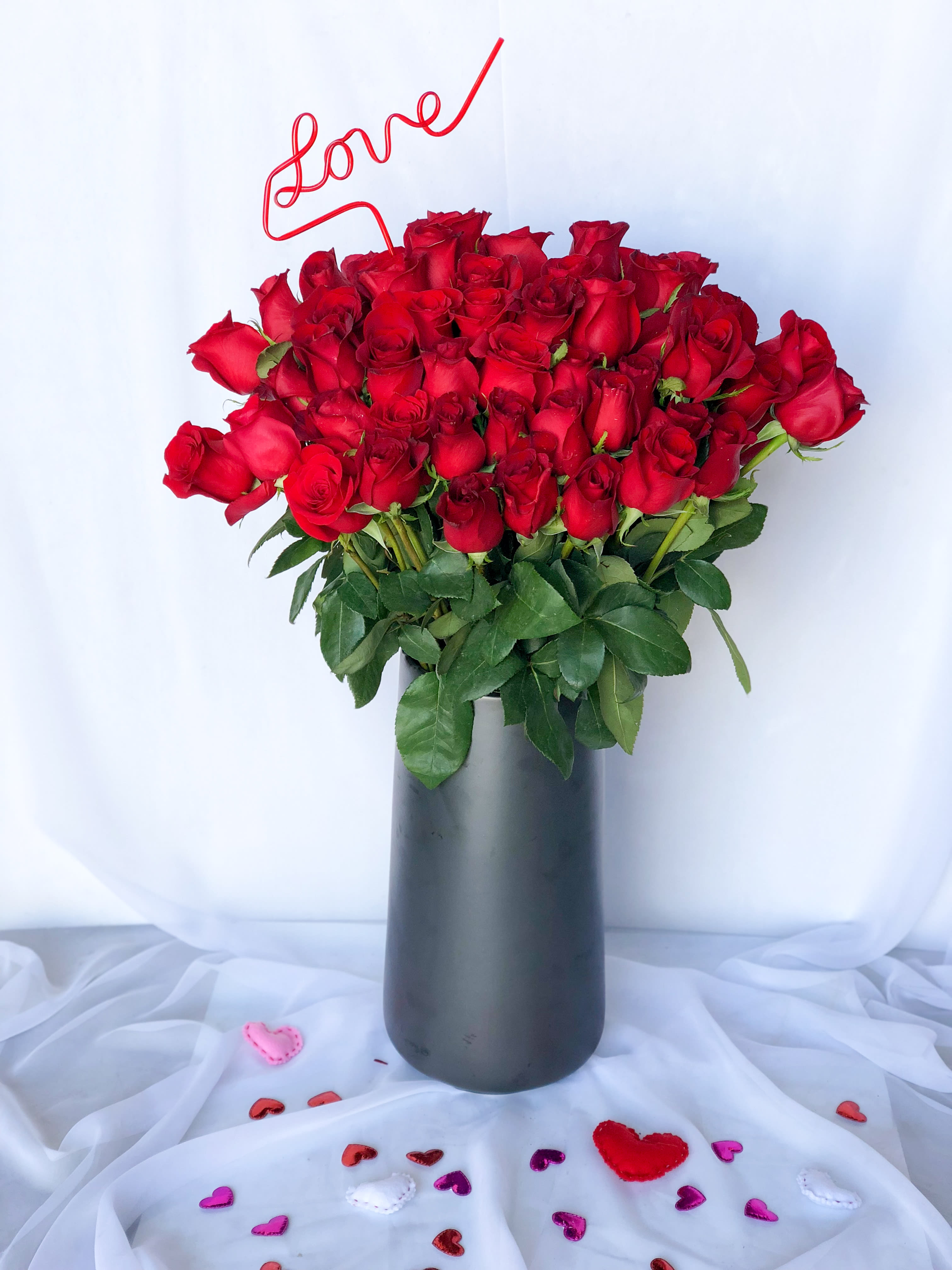"Home Run"  Six Dozen Long Stem Red Roses - This very impressive and very large six dozen long stem red roses is sure to be a home run for your Valentine. We promise. This arrangement is hand crafted in Las Vegas by our all-women design team. Using the freshest blooms from around the world such as Italian ranunculus, Dutch cymbidium orchids, English roses, European hydrangea overflow our custom and unique glass vases. *Please specify color palette when ordering, we will try our best to accommodate requests, but all of our Valentine's Day florals will be a palette of reds, whites, pinks and peaches!*  *It's possible that some days we may not have the exact flowers depending on the season, or exact container specified on the arrangement's description. When this is the case, our bouquets are made with flower substitutions or delivered in a different vase than expected by using substitutions of an equal or higher value. If you'd prefer no substitutions, please send an email or call us after placing your order. Please give us at least three days notice if you're looking for an arrangement with no substitutions. Please be flexible around Valentine's Day we will do our best to deliver a jaw dropping floral arrangement for you! :)  Substitution Policy  In some instances, the florists photo may represent an overall theme or look and include a one-of-a-kind vase which cannot be exactly replicated. Although the actual bouquet may not precisely match the photo, its temperament will. Occasionally, substitutions of flowers or containers happen due to weather, seasonality and market conditions which may affect availability. If this is the case with the gift you've selected, the local florist will ensure that the style, theme and color scheme of your arrangement is preserved and will only substitute items of equal or higher value.