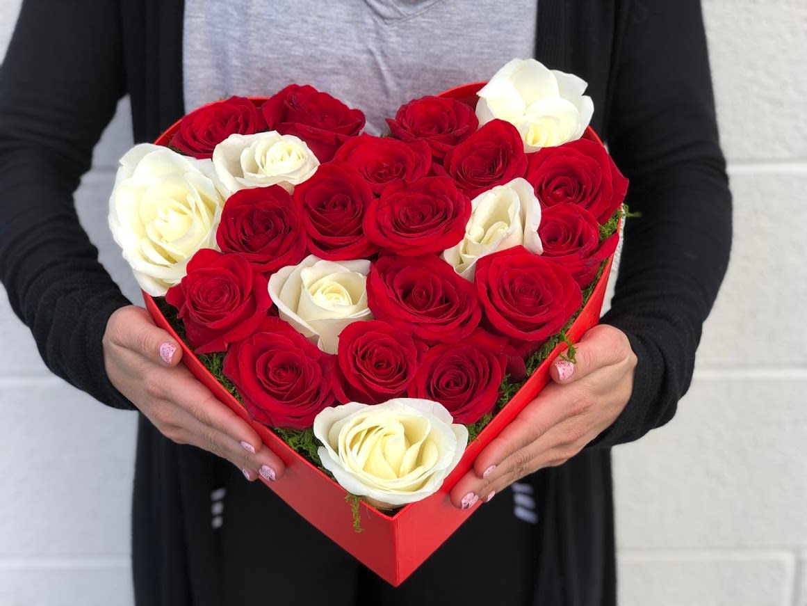 Heart-shaped box of red and white roses held in two hands