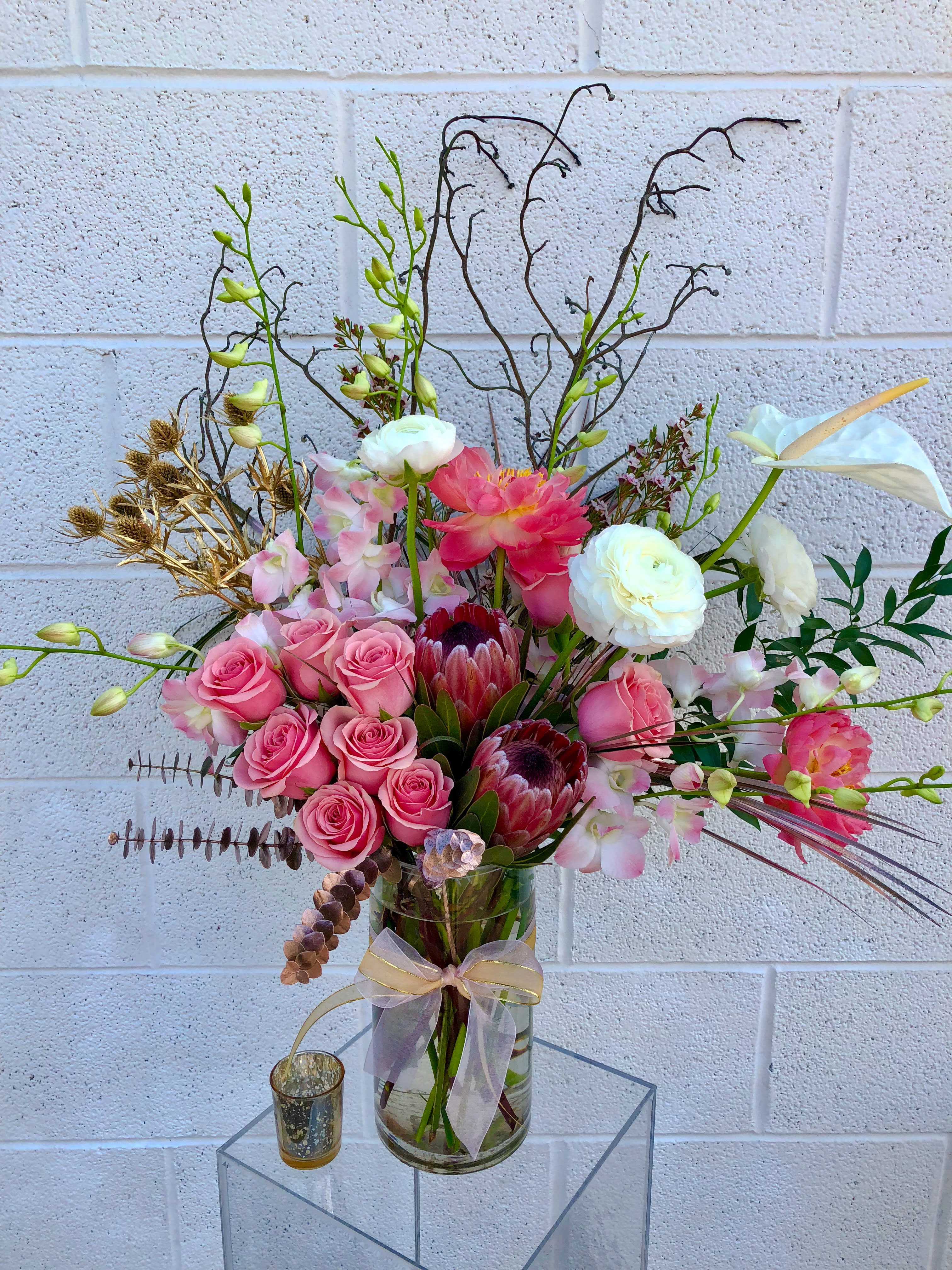 Pink roses and white calla lilies in a glass vase with a ribbon