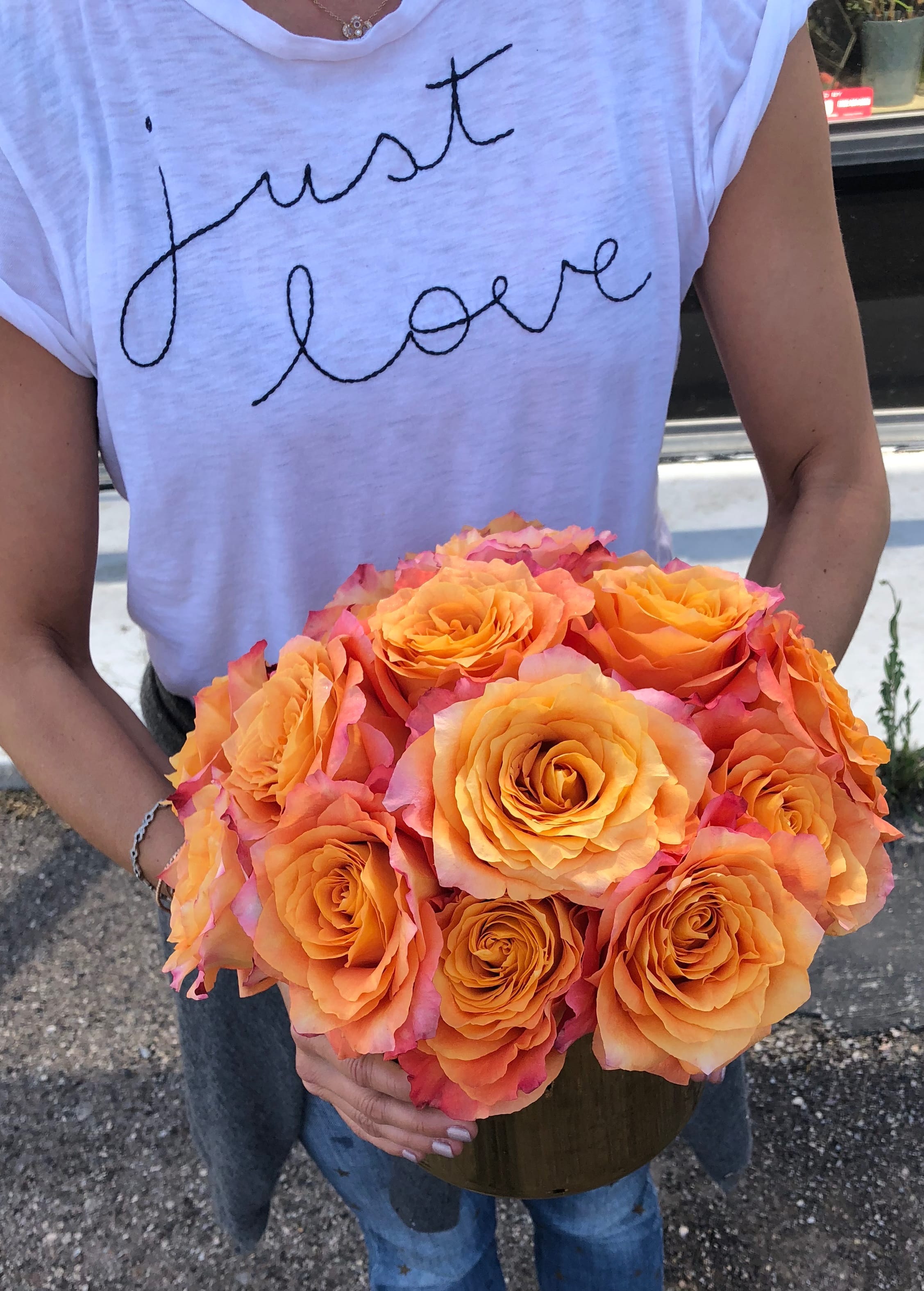 Person holding a bouquet of orange roses in a vase