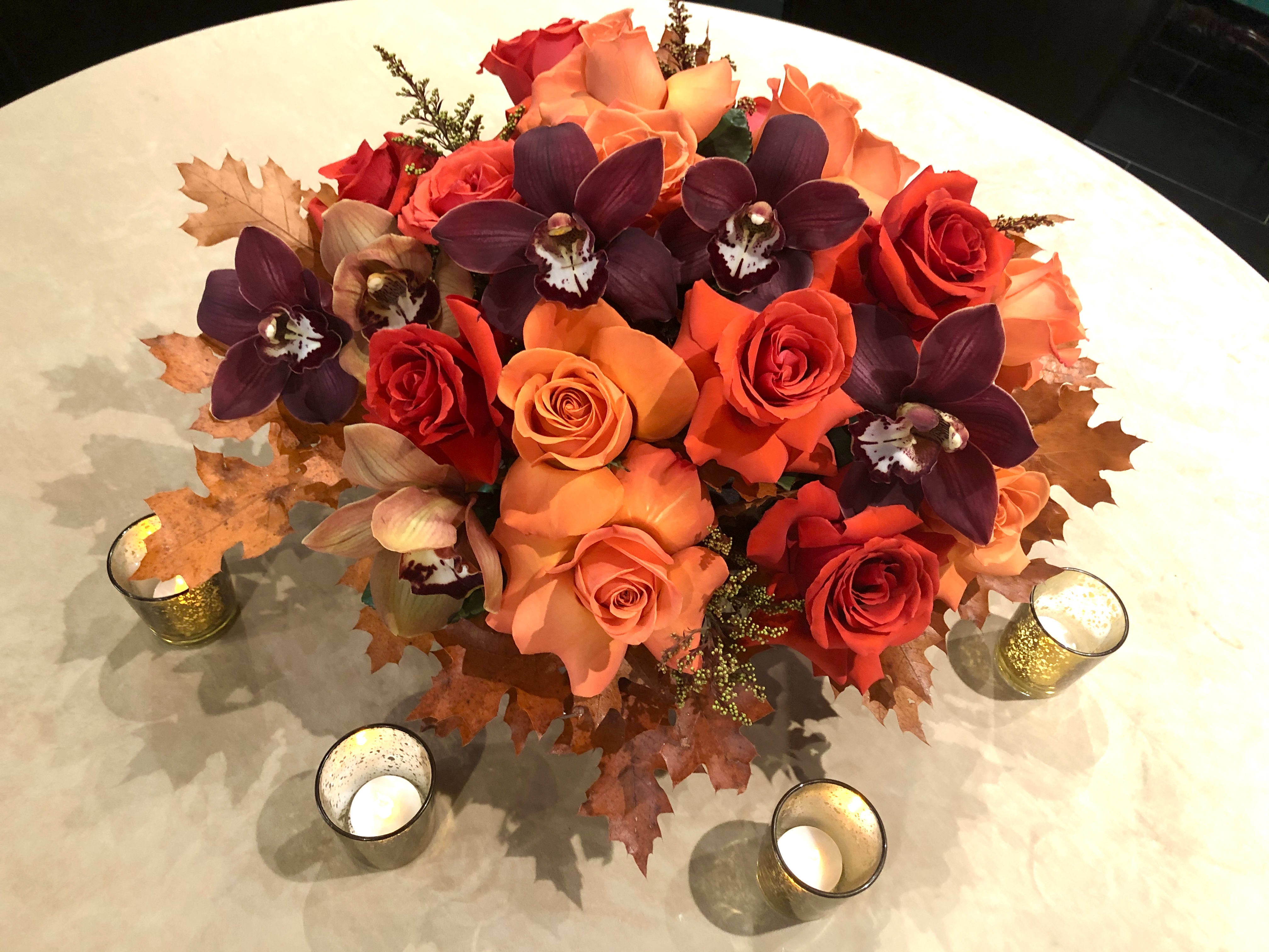 Large Thanksgiving Centerpiece - This low and lush arrangement is the PERFECT centerpiece for your festivities this season! Filled with flipped out roses, cymbidiums, and other coordinating seasonal elements. 