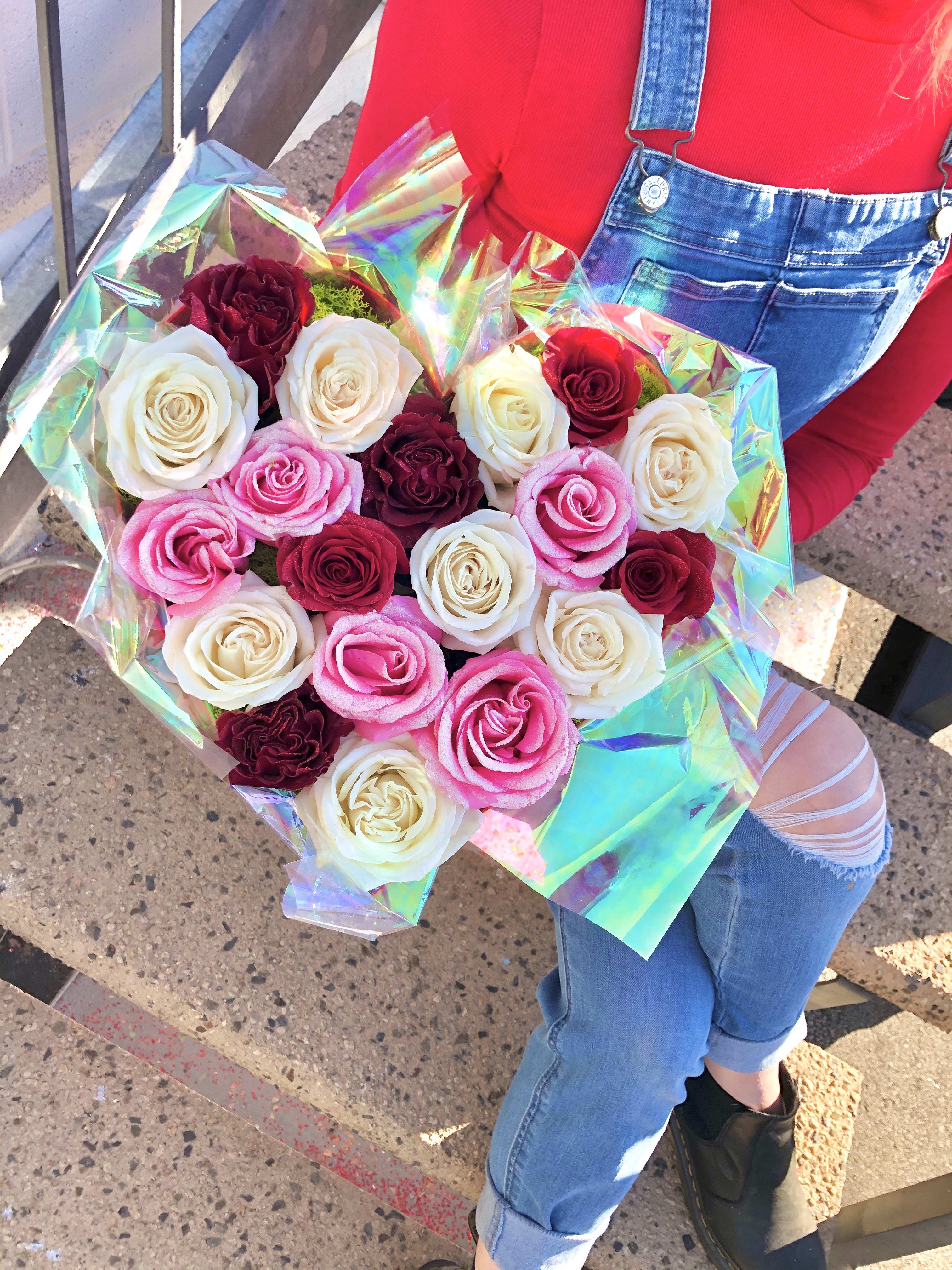 Bouquet of pink, white, and burgundy roses wrapped in iridescent paper