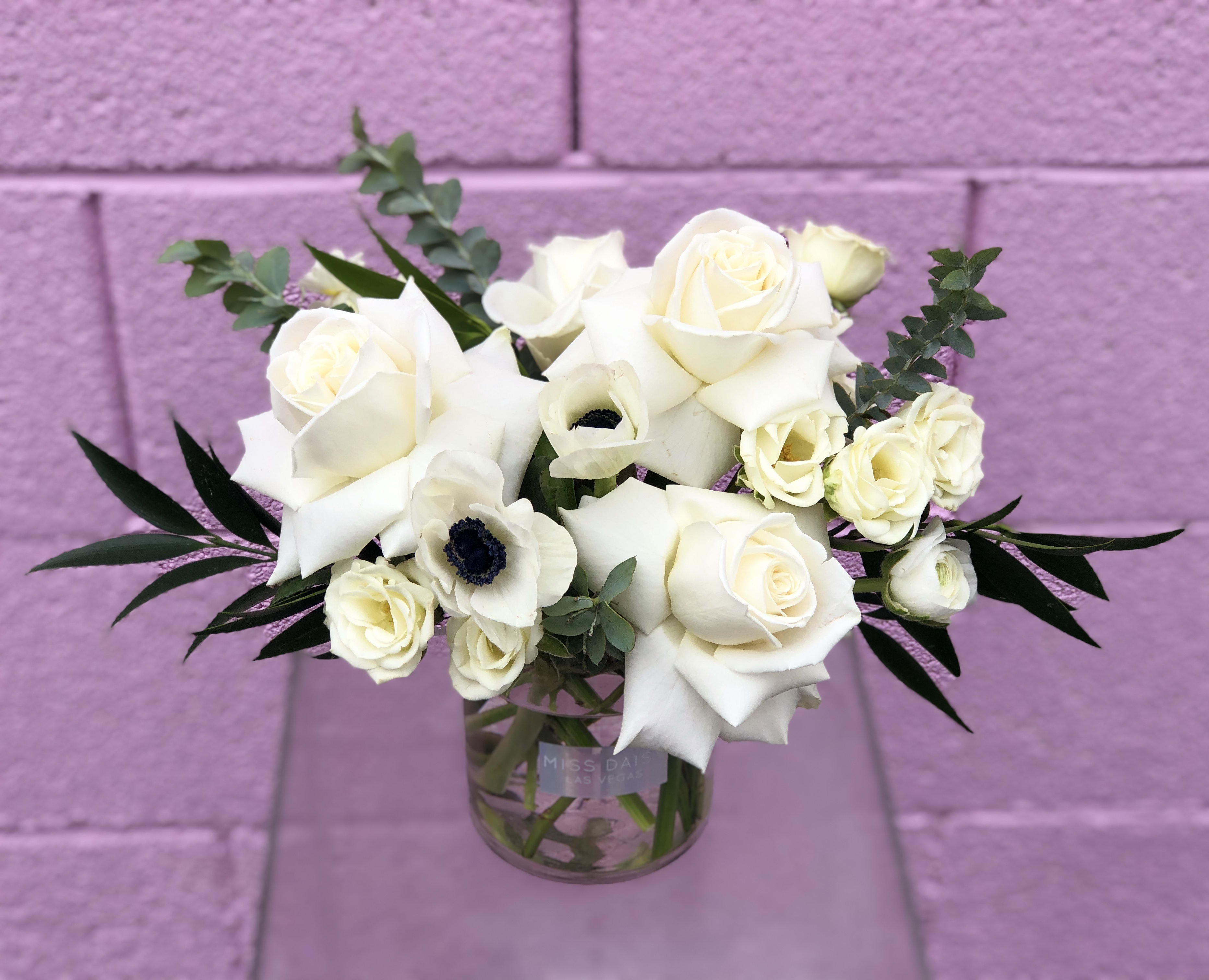 White roses and calla lilies in a clear glass vase