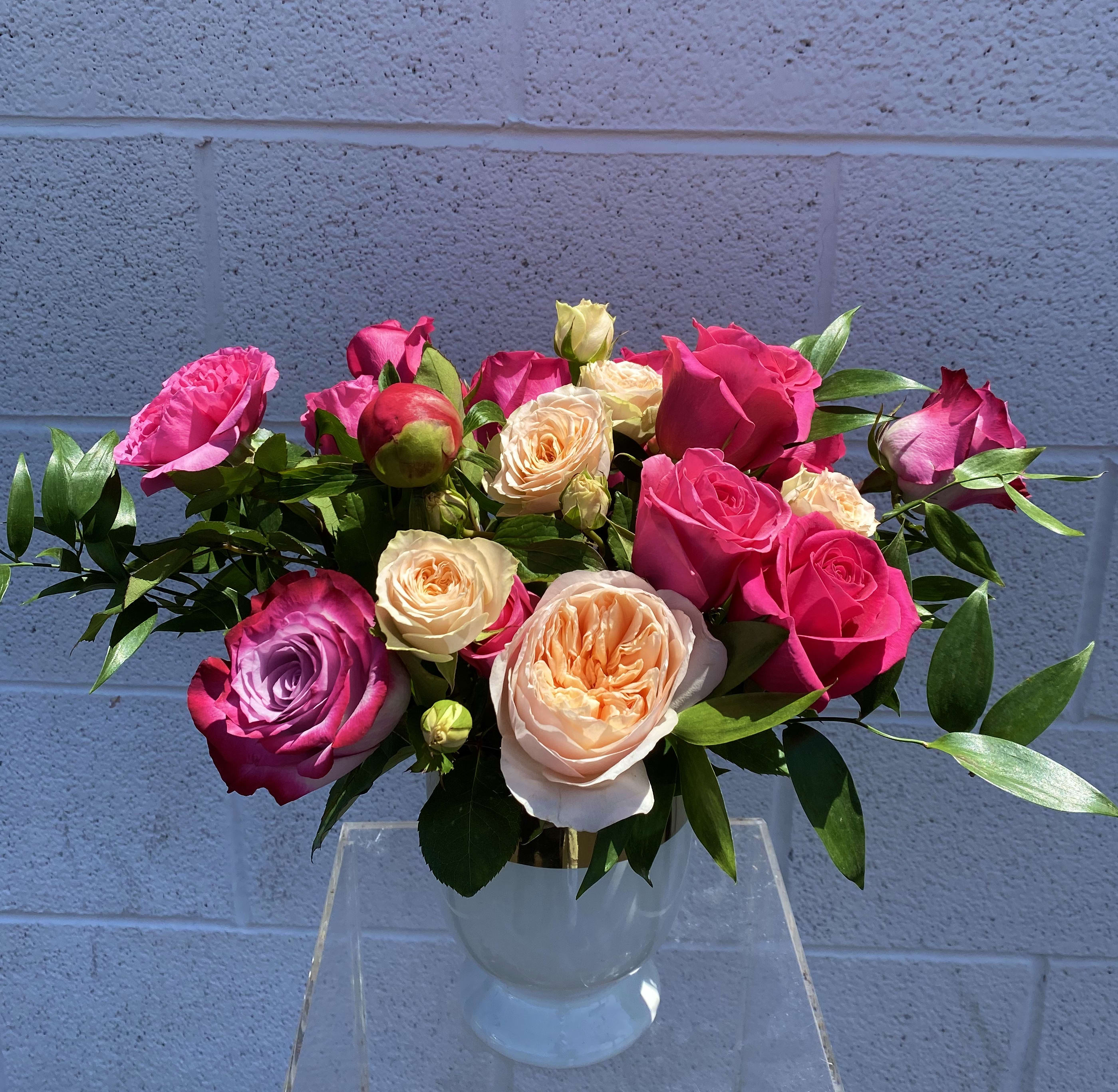 Bouquet of pink, peach, and lavender roses in a clear vase