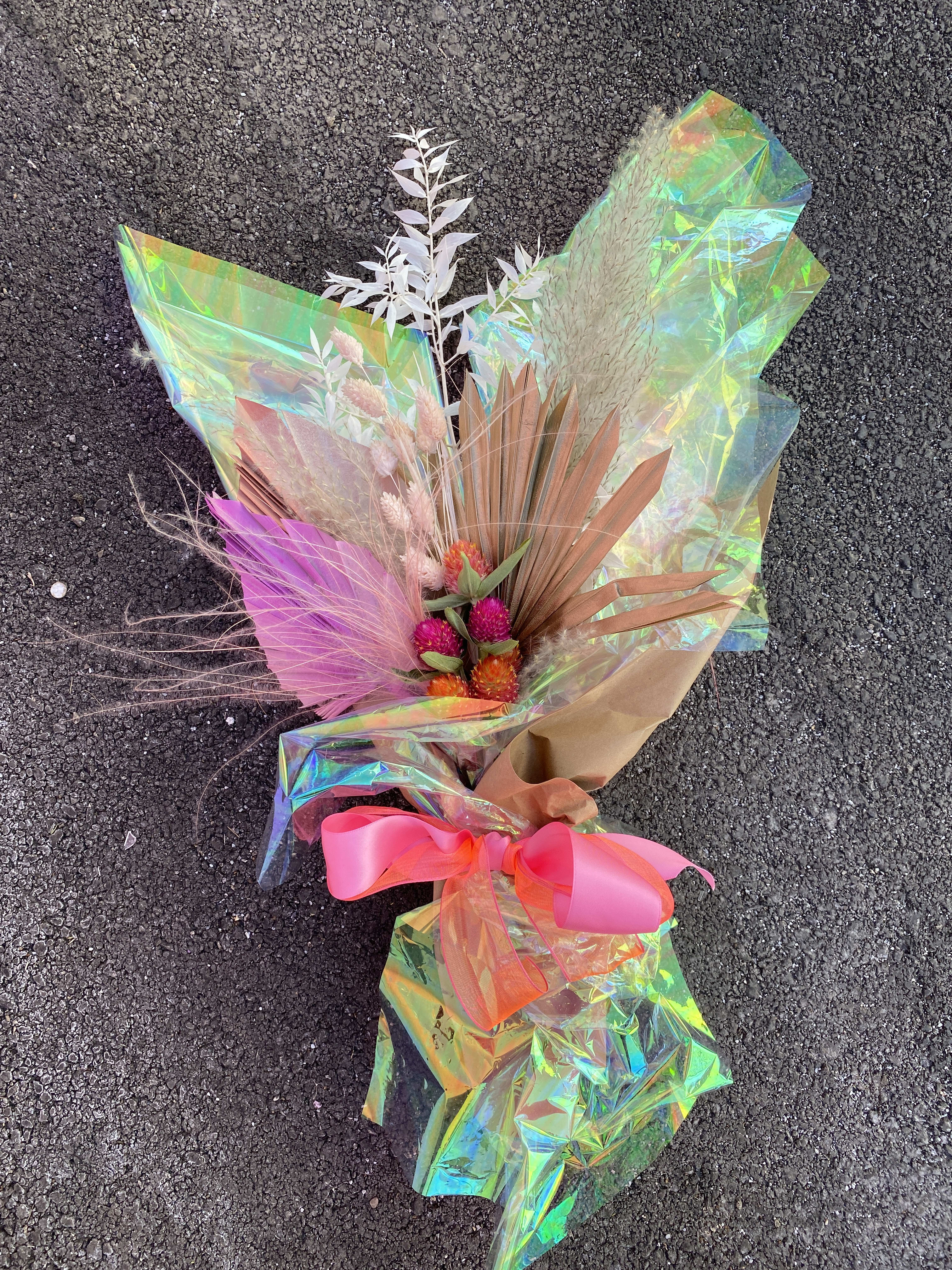 Bouquet with pink and orange dried flowers wrapped in iridescent paper