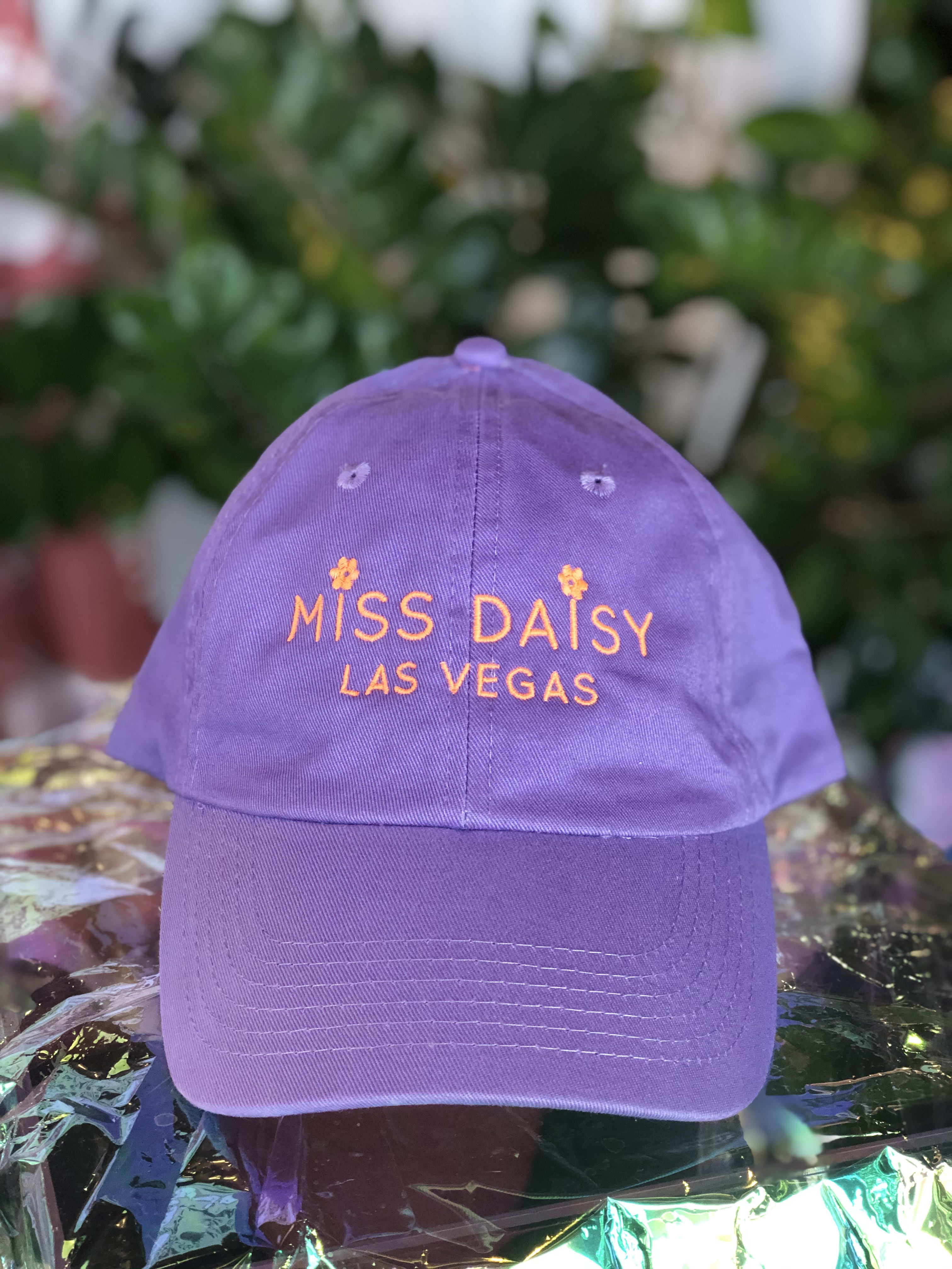 Purple baseball cap with orange embroidered text reading "Miss Daisy Las Vegas"
