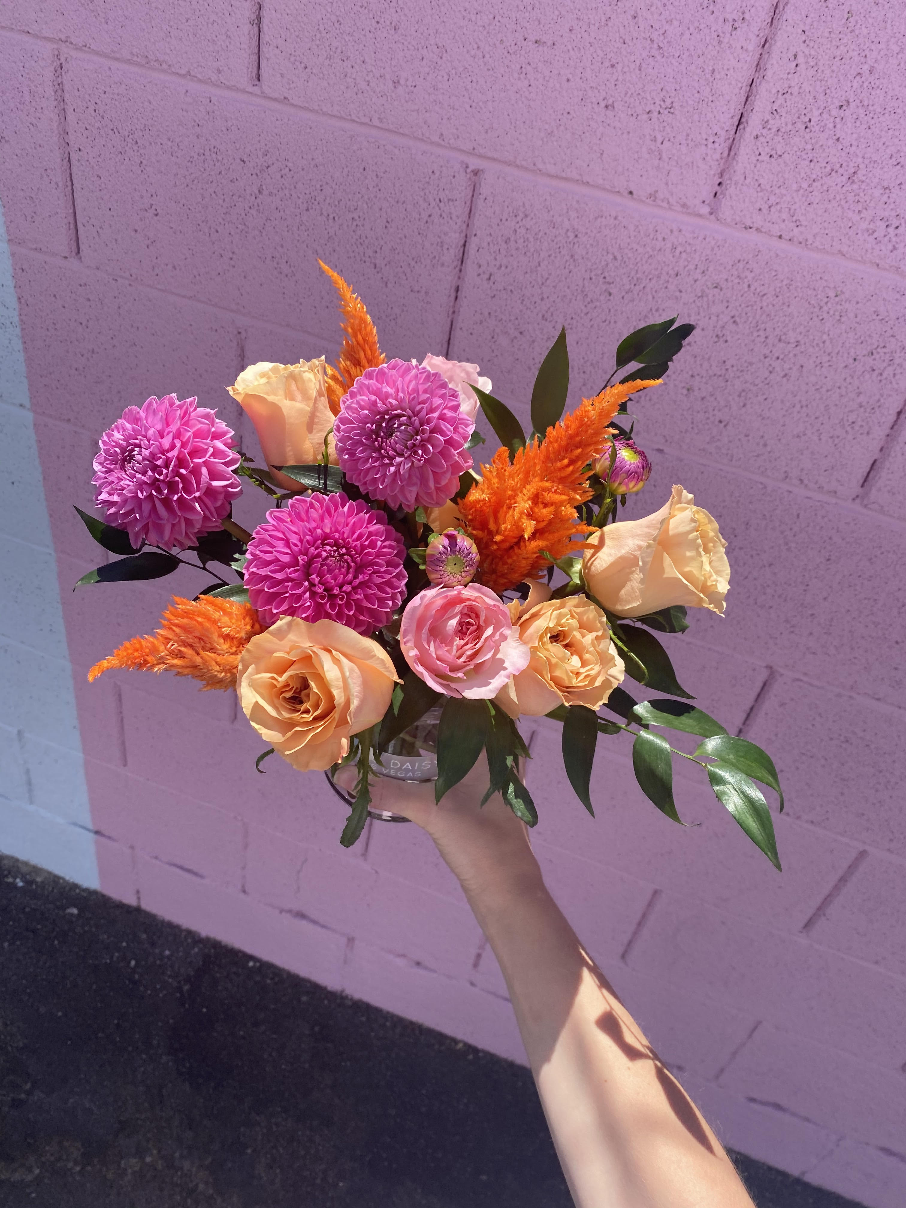 Handheld bouquet of pink and peach flowers with orange accents