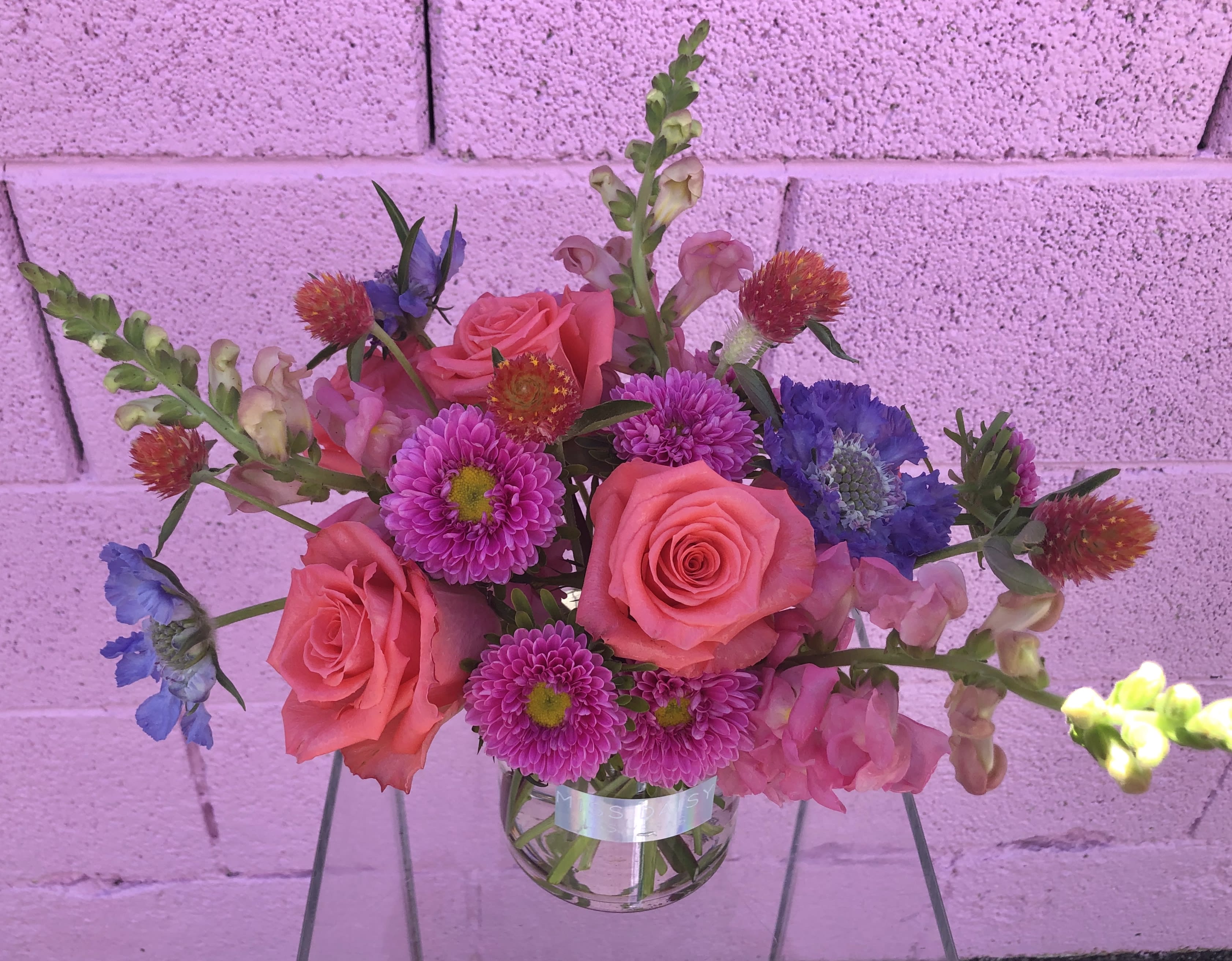 Pink roses and purple flowers in a clear glass vase