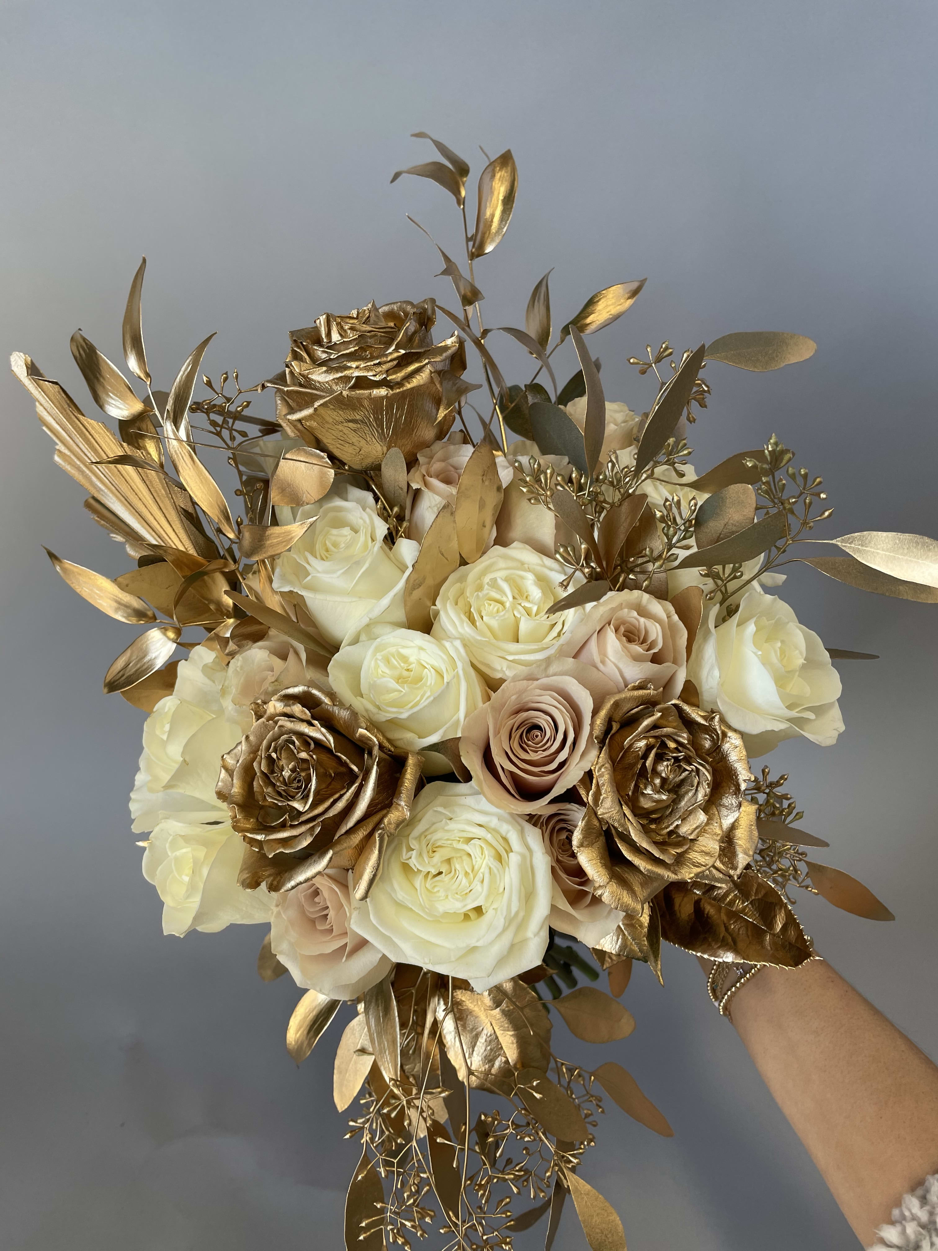 Bouquet of cream and gold roses with metallic foliage