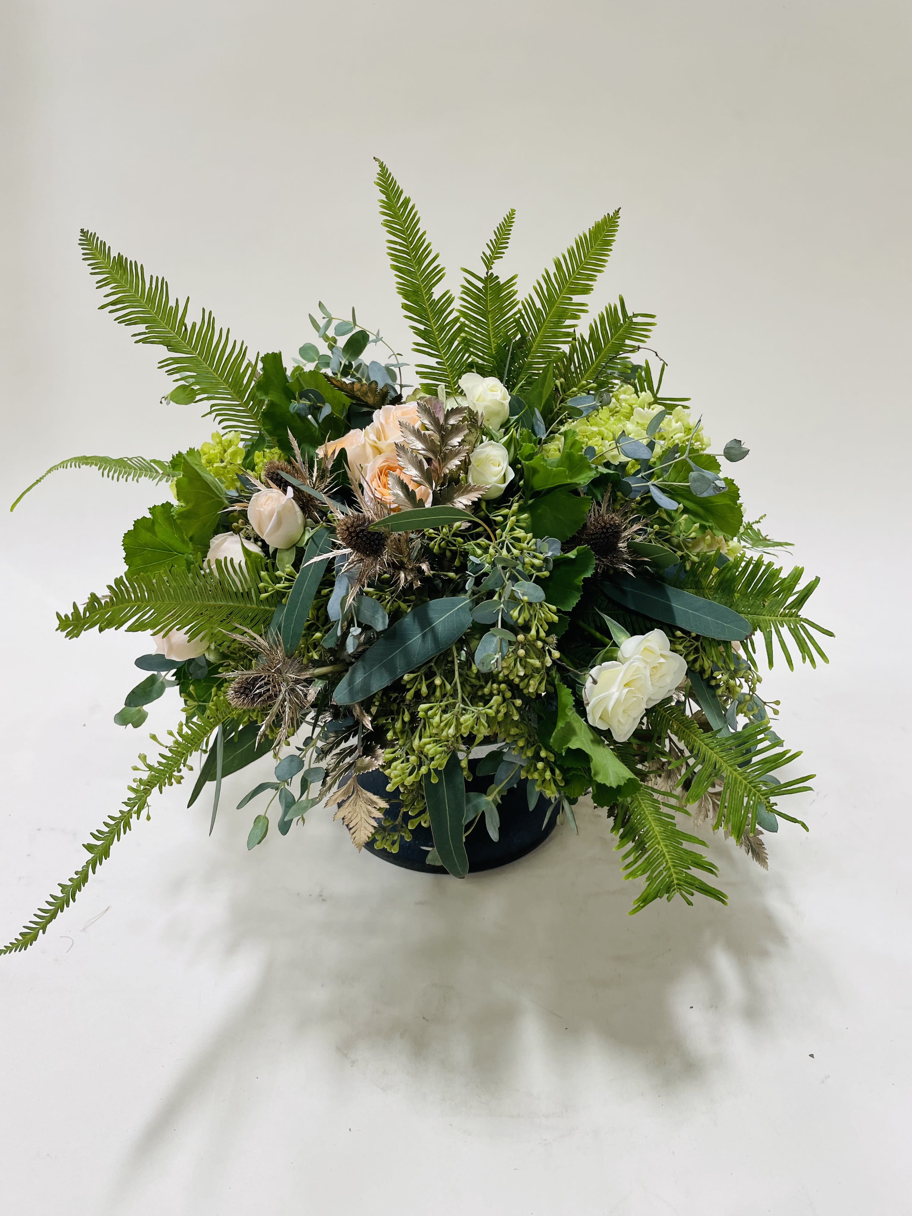 Low floral arrangement with white and peach roses in a dark container